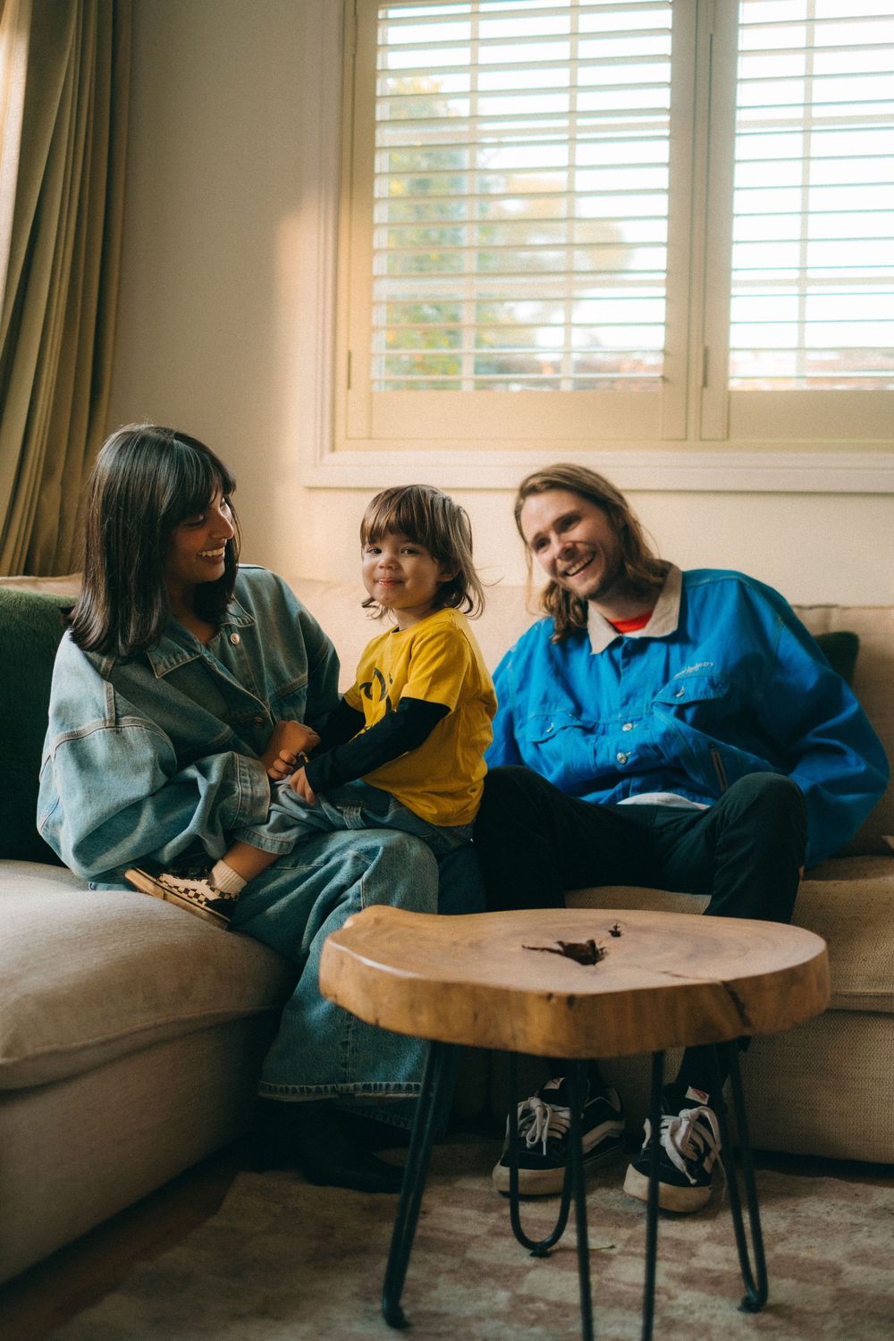 A casual family moment captured on a couch with a wooden coffee table in the foreground.