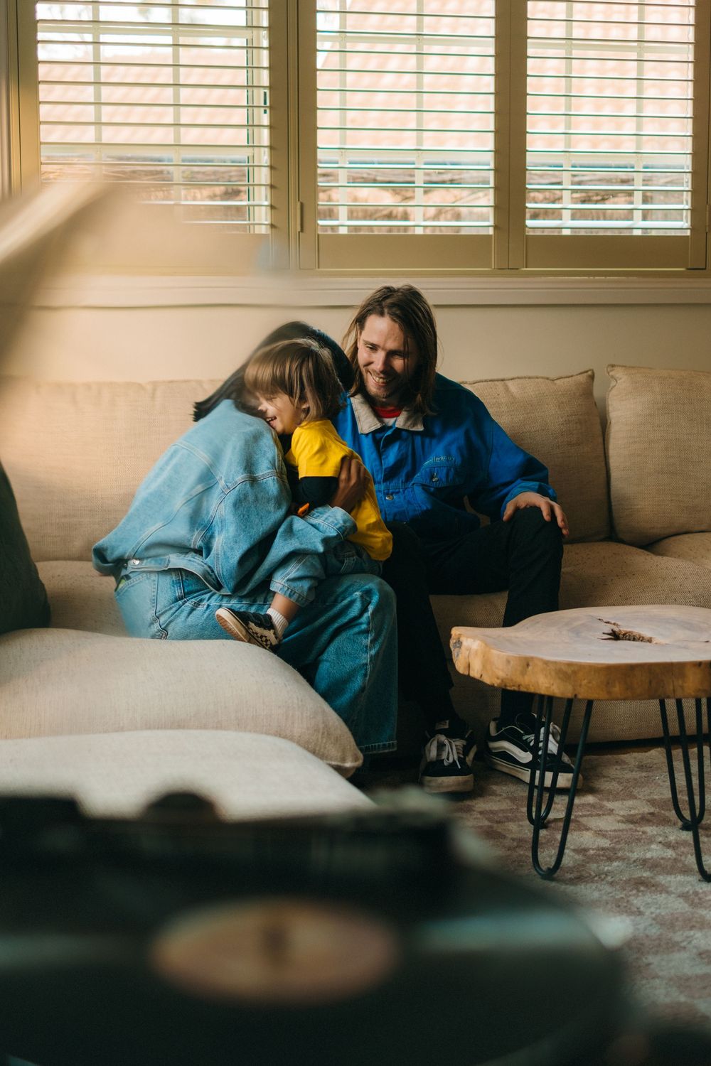 Family relaxing together on a cozy couch near a window with sunlight streaming in.