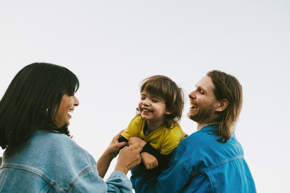 Playful outdoor family moment captured against bright white background.