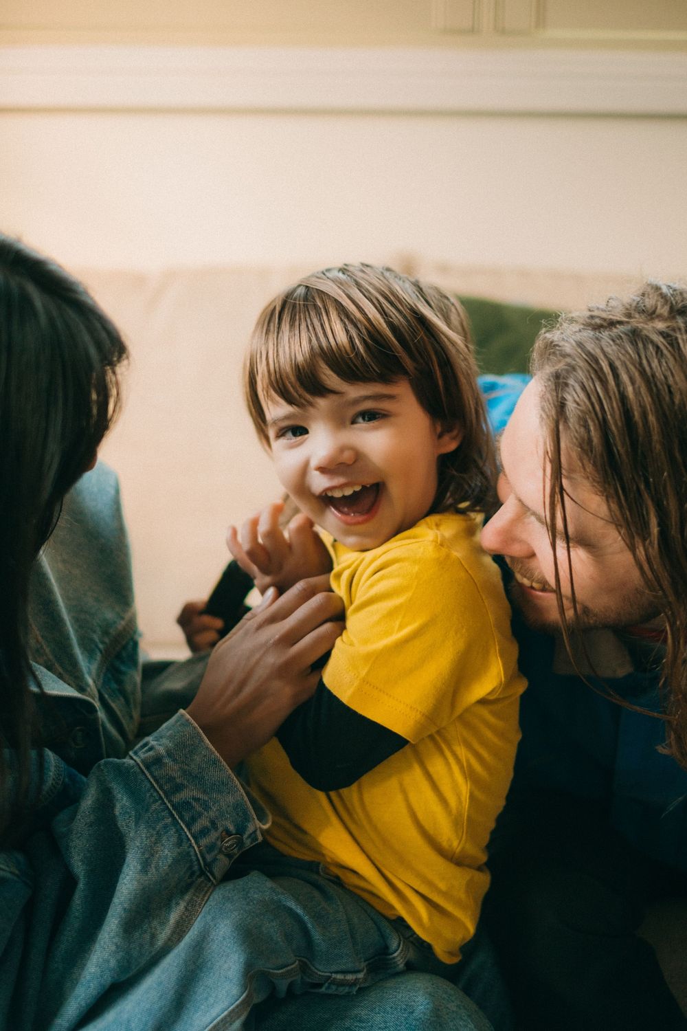 Candid moment of laughter and play on a living room couch.