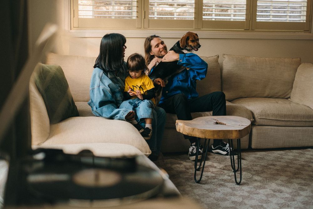 Intimate family moment shared on a grey sofa with a small round table nearby.