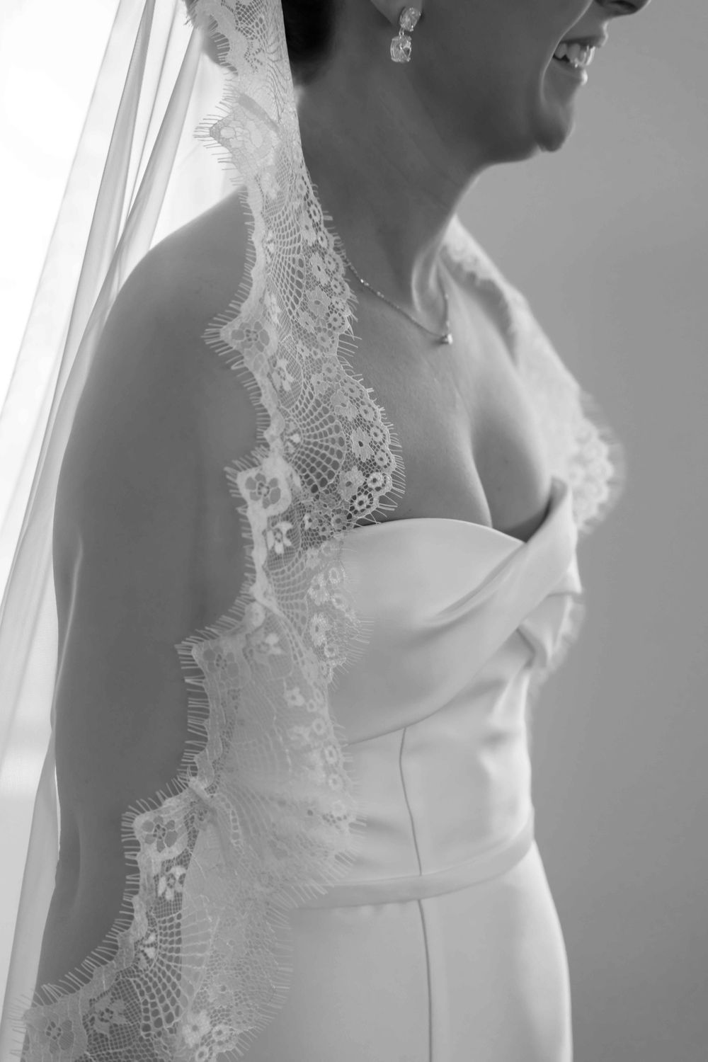 Black and white detail shot of wedding dress bodice with delicate lace veil trim.