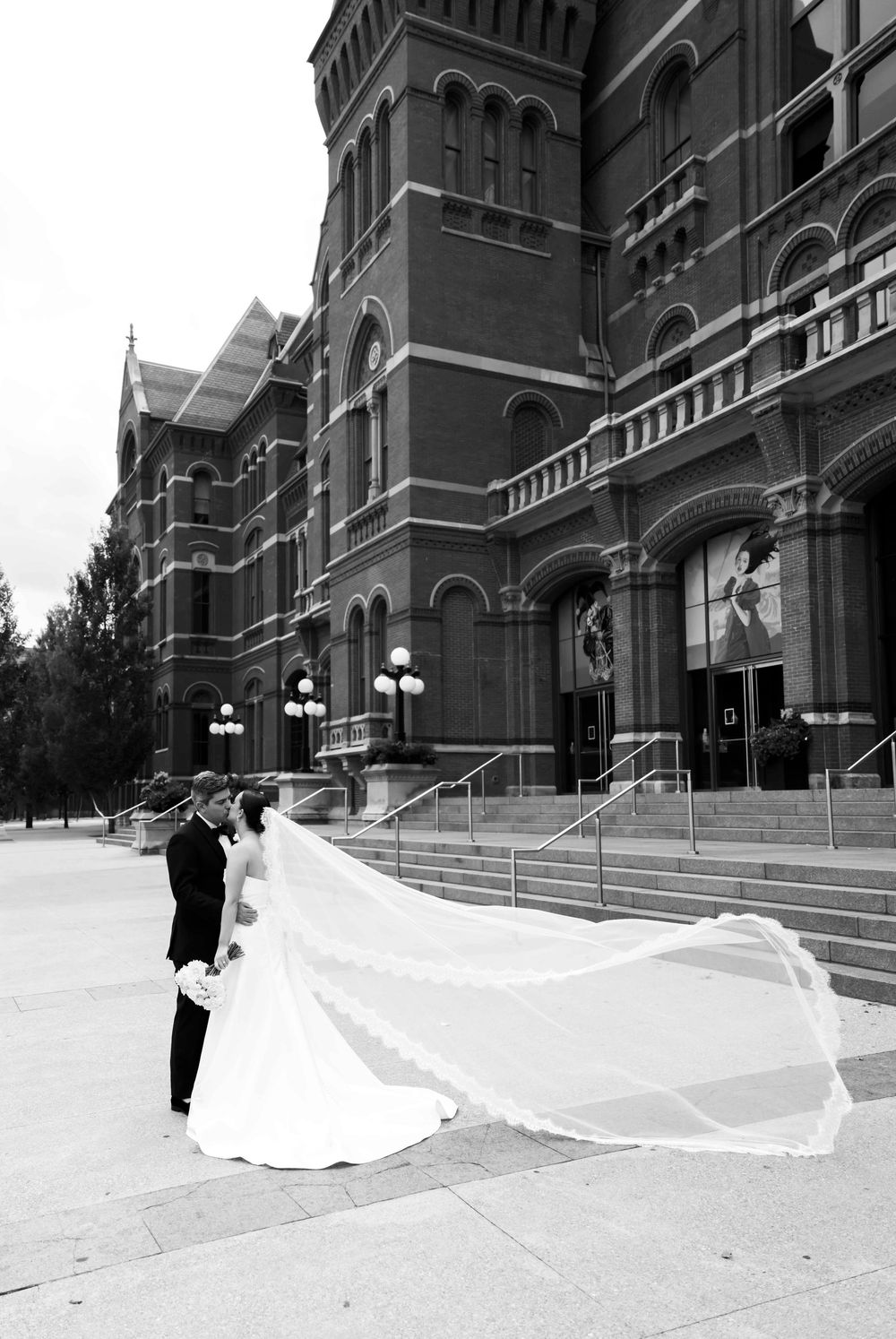 Elegant bridal photos showing flowing wedding veil billowing in the wind against Gothic church architecture exterior steps.