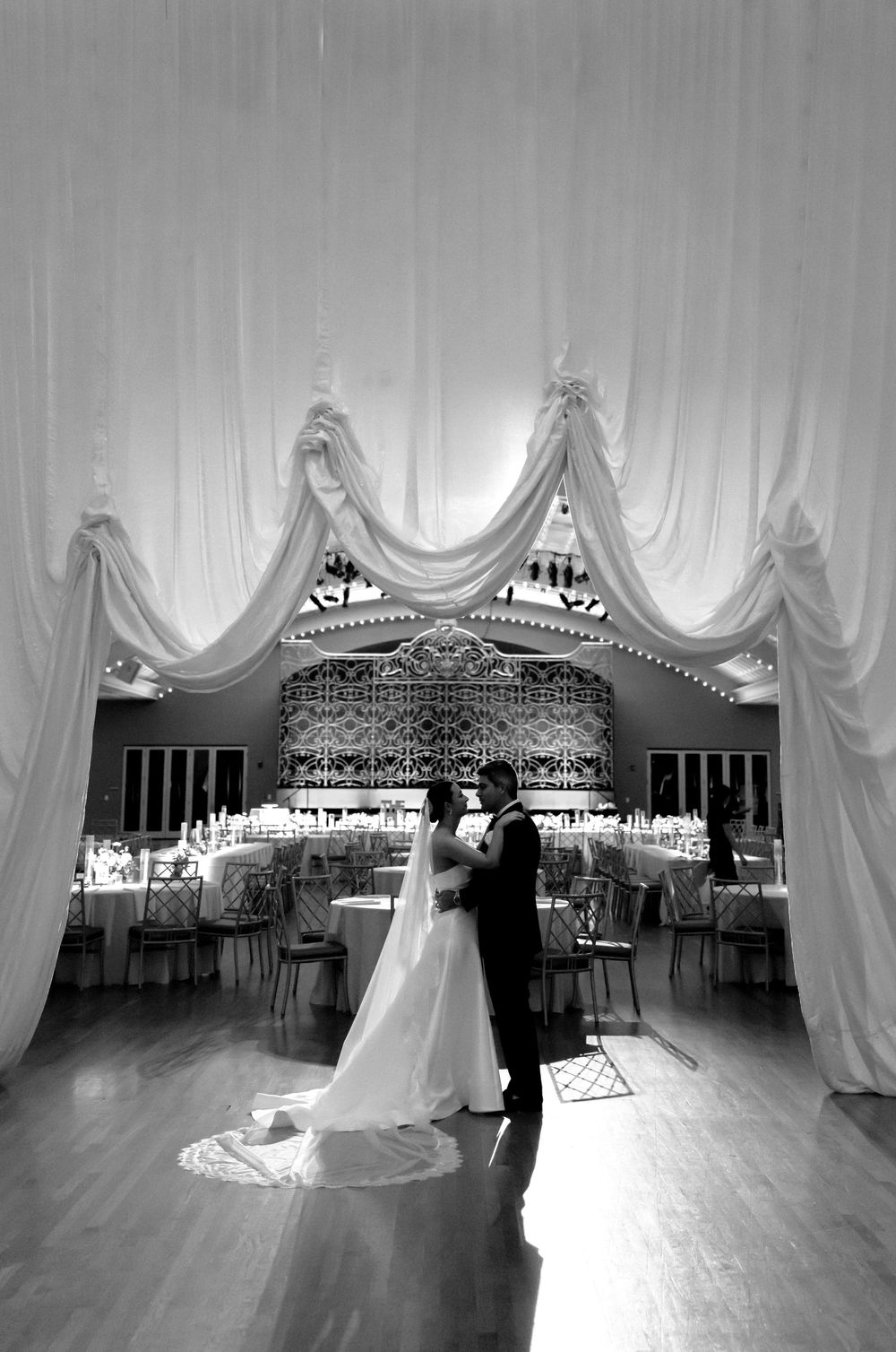First dance at elegant reception with white drape decor and illuminated dance floor against romantic lighting.