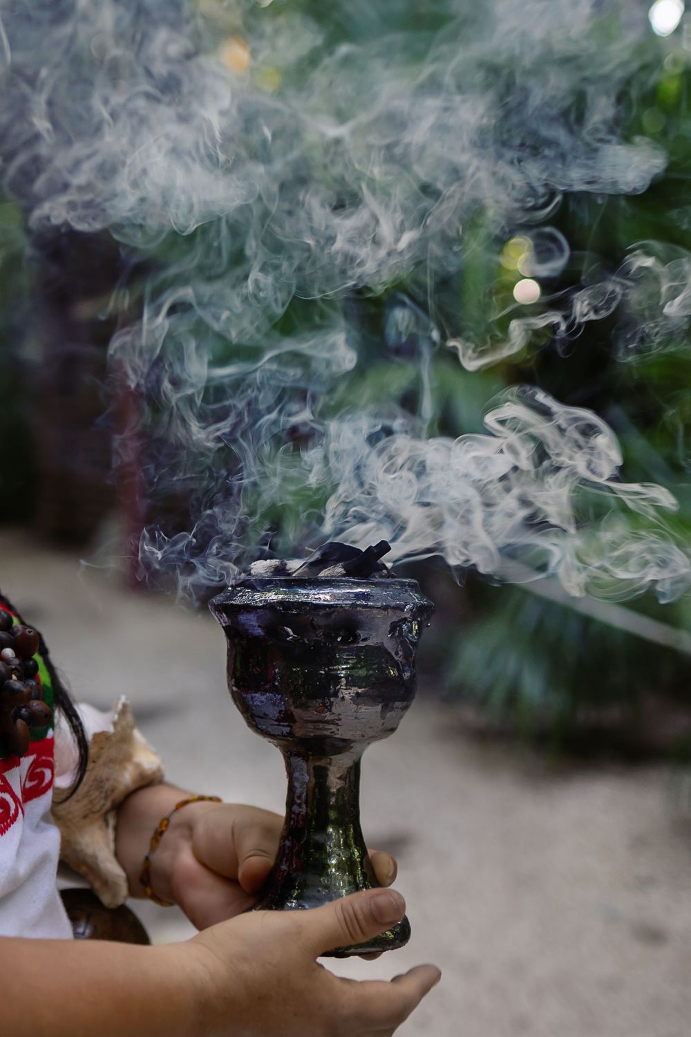 Close-up of a shaman holding a smoking copal chalice in a traditional Mayan ritual.