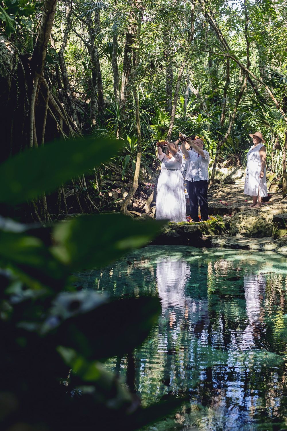 Guests and couple celebrating with flower petals at the end of a spiritual cenote ceremony.