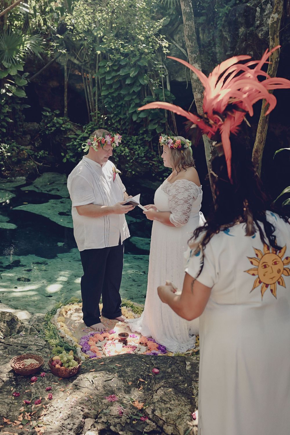 Bride and groom standing on a flower mandala during a Mayan elopement by a sacred cenote.