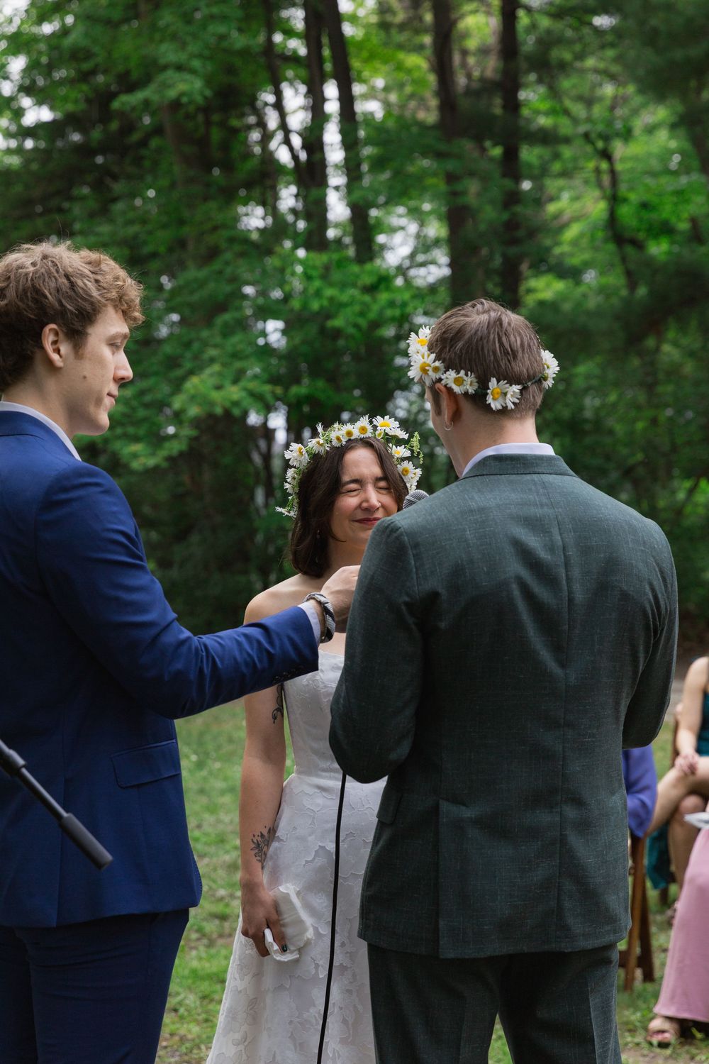 Wedding ceremony moment captured in a natural forest setting with flowers and greenery.