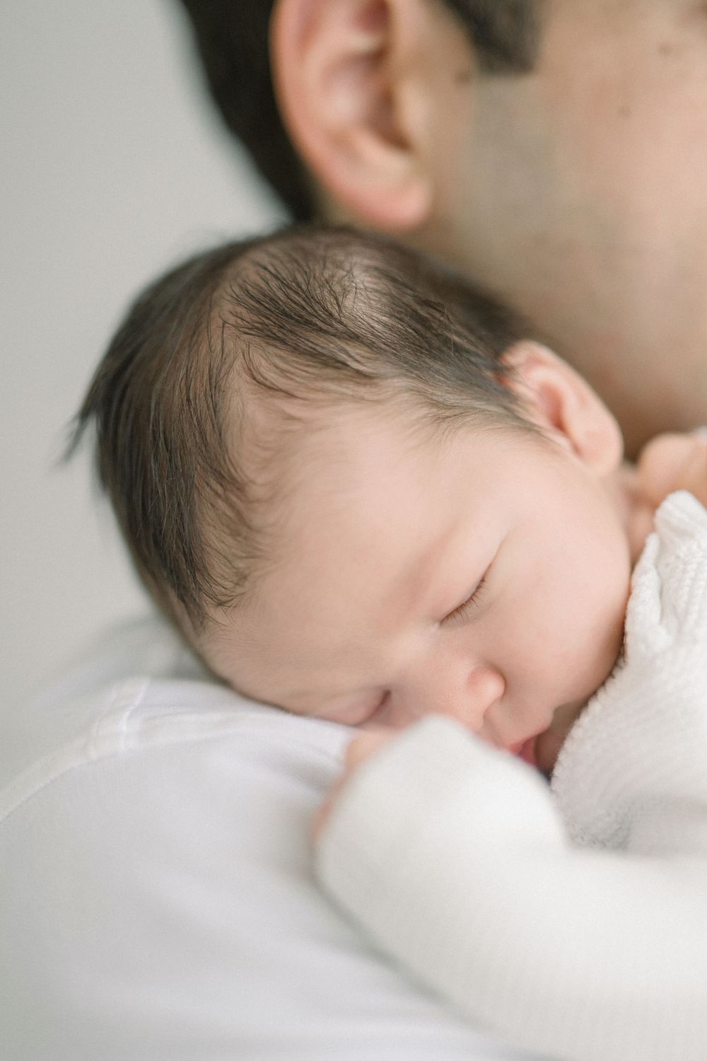 A series of peaceful sleeping baby portraits in soft natural light against white bedding showing different gentle angles.