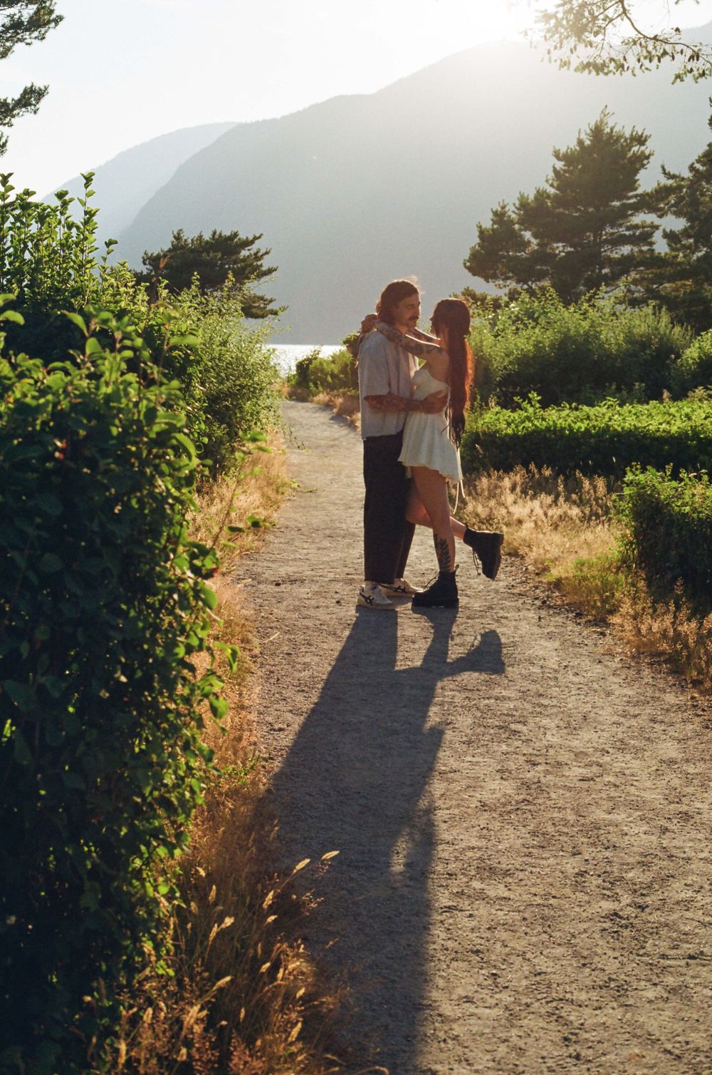 Silhouetted figures walking on scenic coastal trail during golden hour.