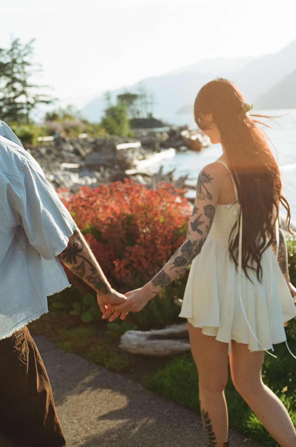 Couple dancing together on a scenic coastal path during golden hour.