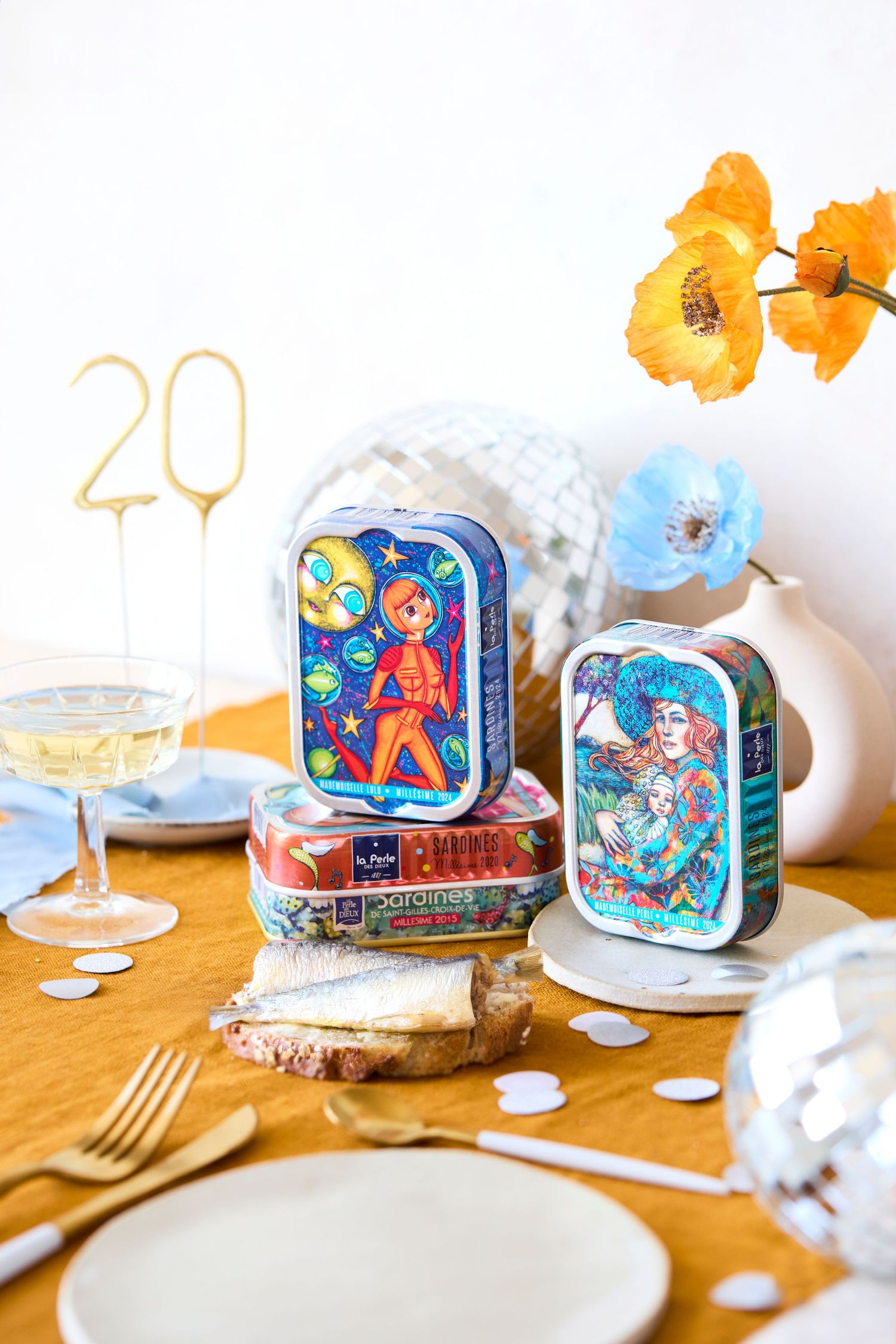 Vintage decorative tin boxes and party decor displayed on a table with champagne glasses and golden number 20.