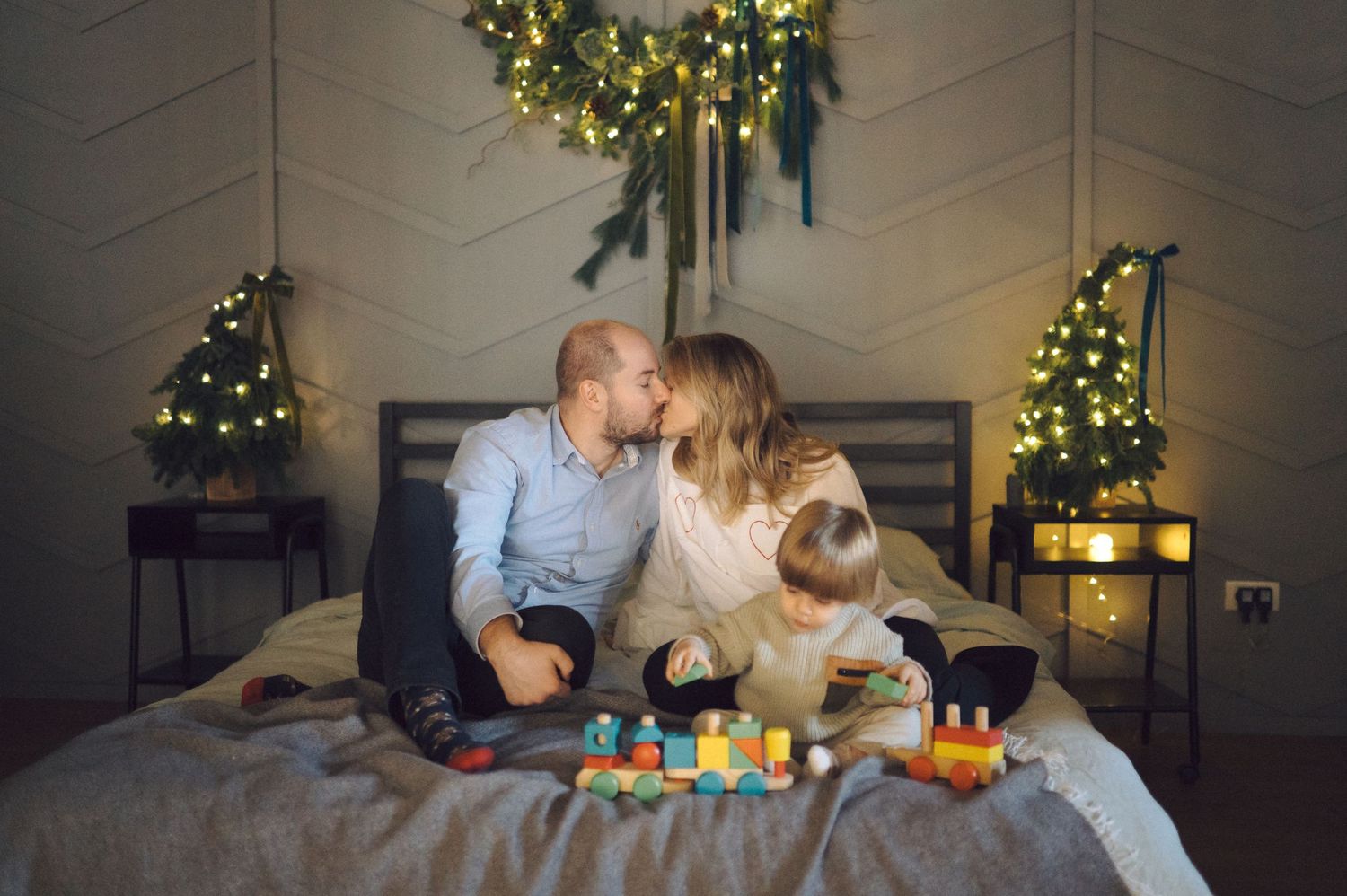 Family shares tender moments together in a holiday-decorated living room with greenery and lights.