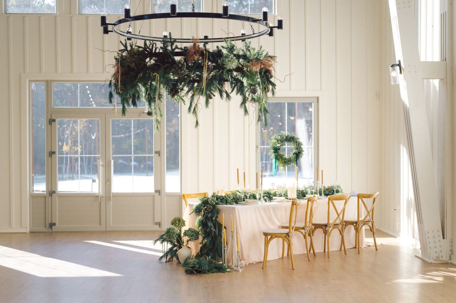 Light-filled studio space with beige walls, hardwood floors, track lighting and scattered plants creates a serene atmosphere.