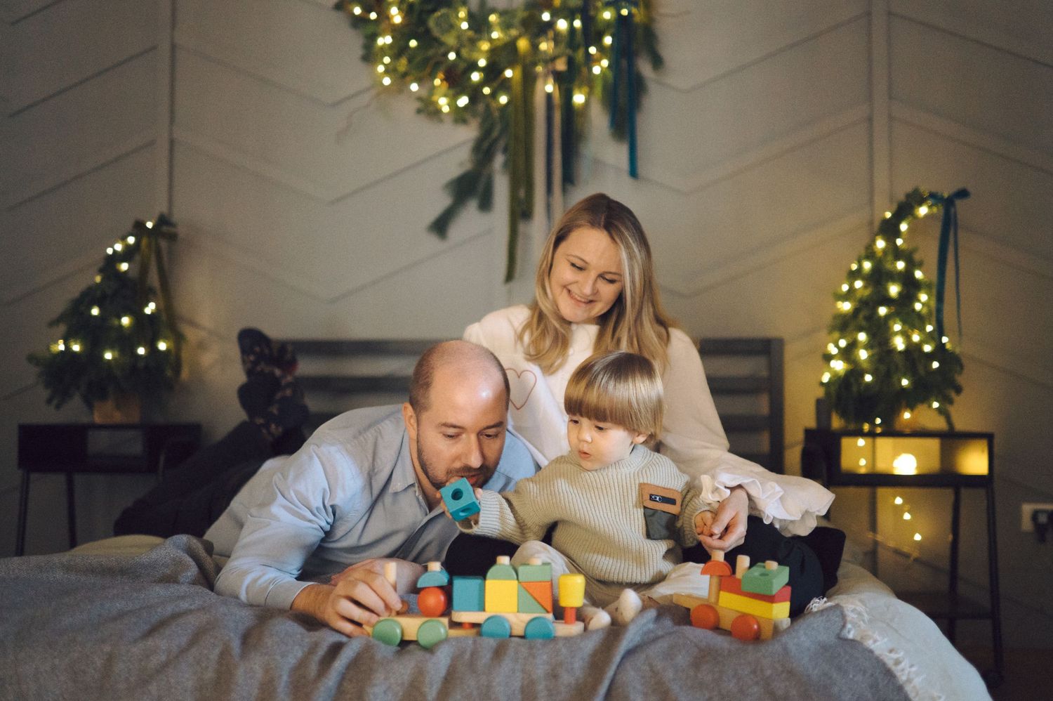 Parent and child enjoy quality time together playing with colorful building blocks near a Christmas tree with twinkling lights.