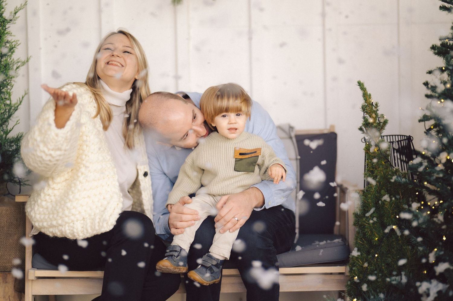 Family members show joy and holiday spirit as bokeh lights twinkle around a Christmas tree backdrop.