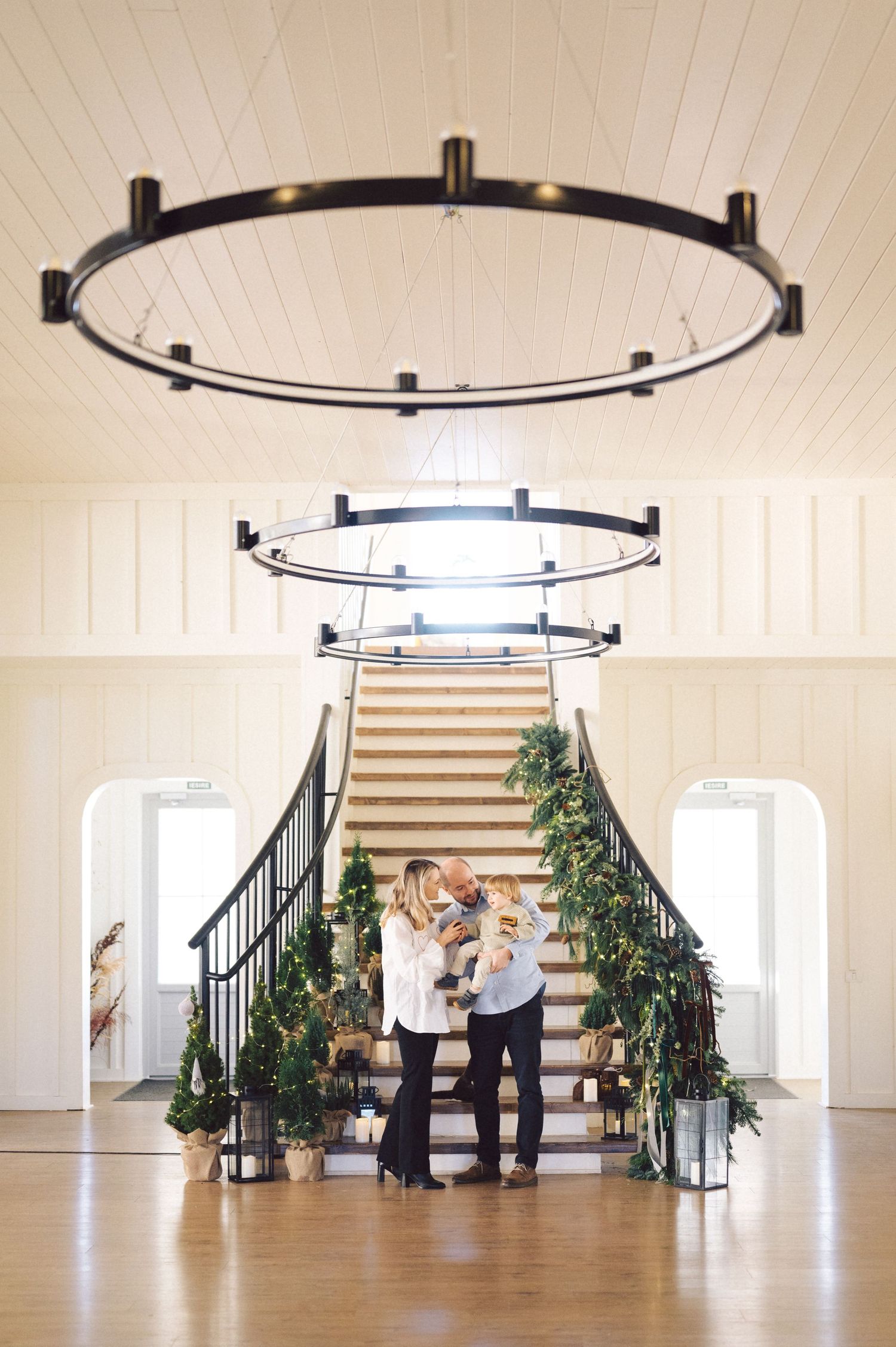 Romantic couple practicing ballroom dance steps together in an elegant white studio with staircase and modern lighting.