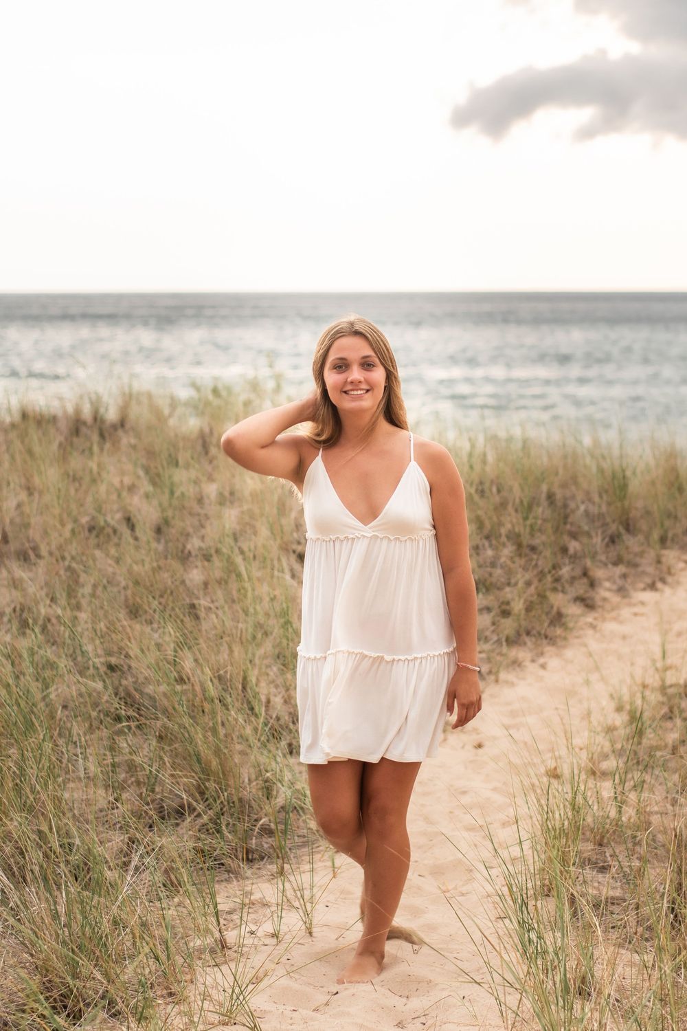 Senior girl walking through the dune grass, with Lake Michigan in the background.