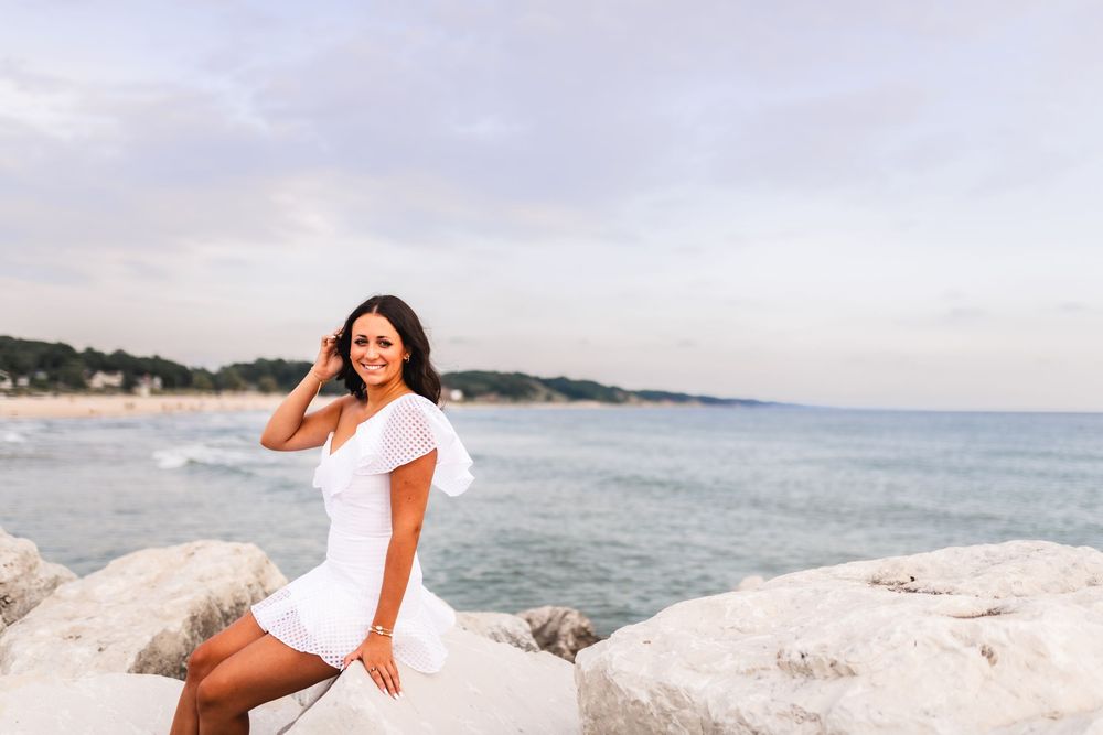 High school senior girl sitting on a rock near Lake Michigan.