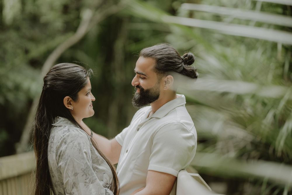 A couple shares an intimate moment outdoors surrounded by lush greenery and natural light.