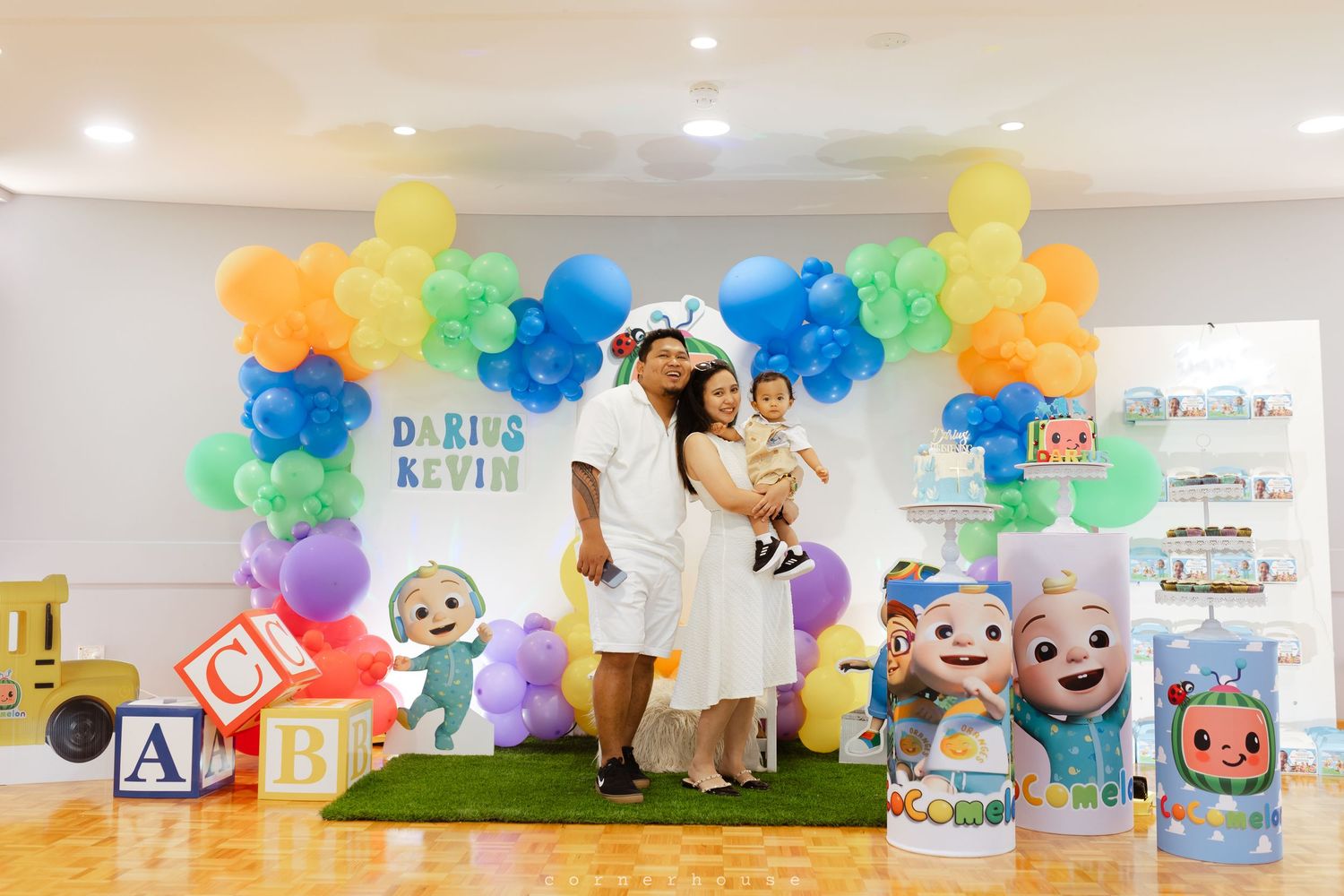 Colorful balloon arch installation with rainbow hues decorates a modern interior space for a festive celebration.