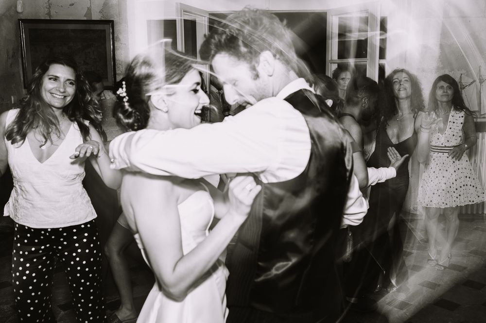 A couple dances together at a party while other guests smile in the background at a vintage black and white celebration.