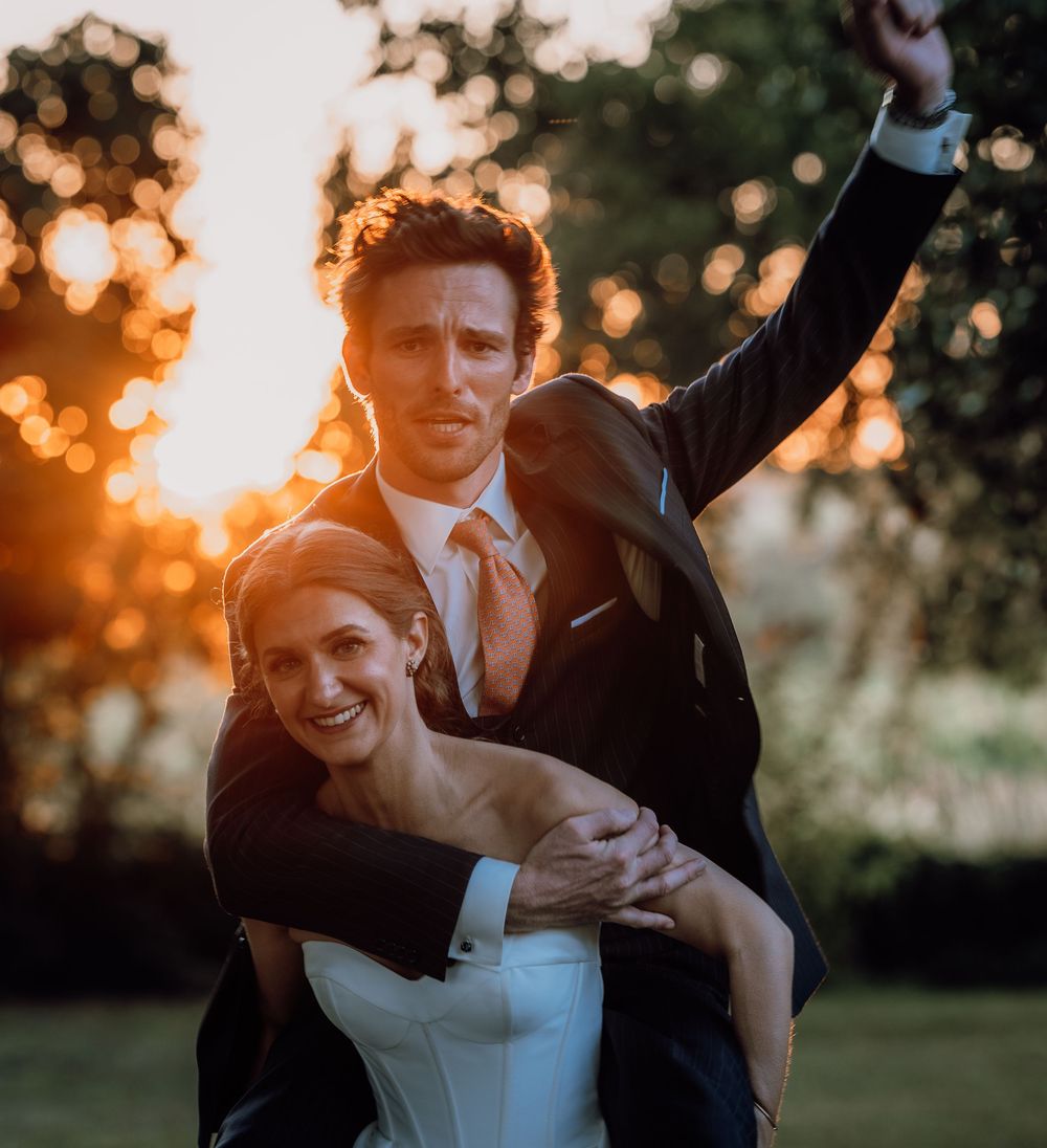 A joyful romantic moment between a couple embracing during golden hour sunset in a garden setting.