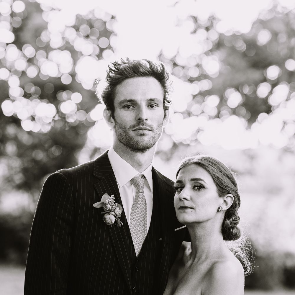 An artistic black and white portrait of a couple in formal wedding attire with dreamy bokeh background.