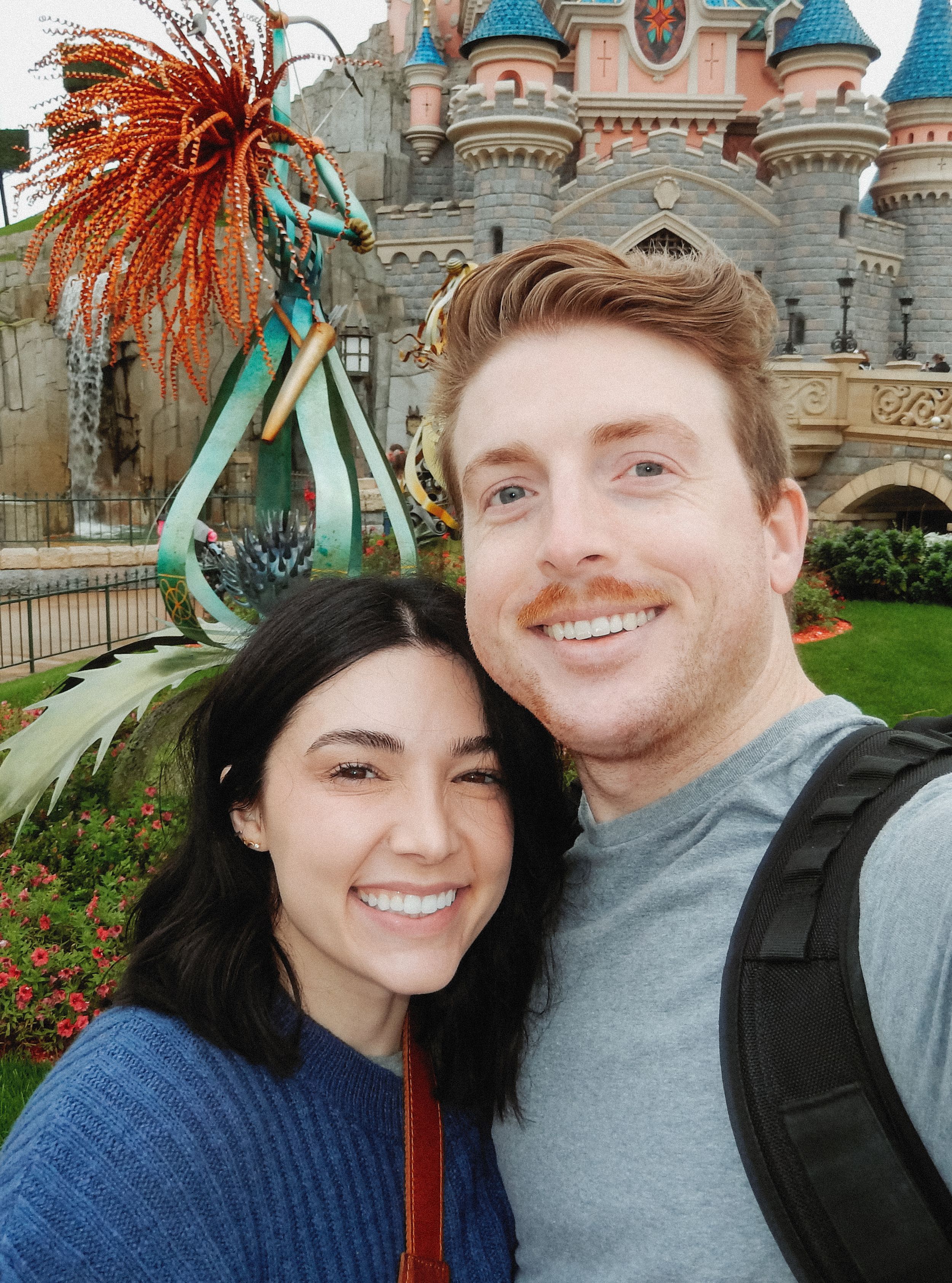 Couple taking selfies in front of Disneyland castle with festive decorations.
