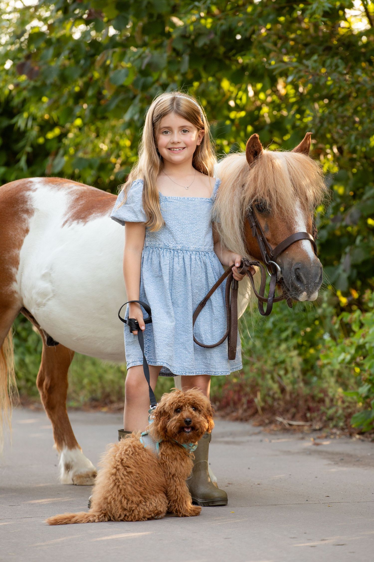 Young equestrian poses with palomino pony in a series of natural outdoor portraits showing their special bond.