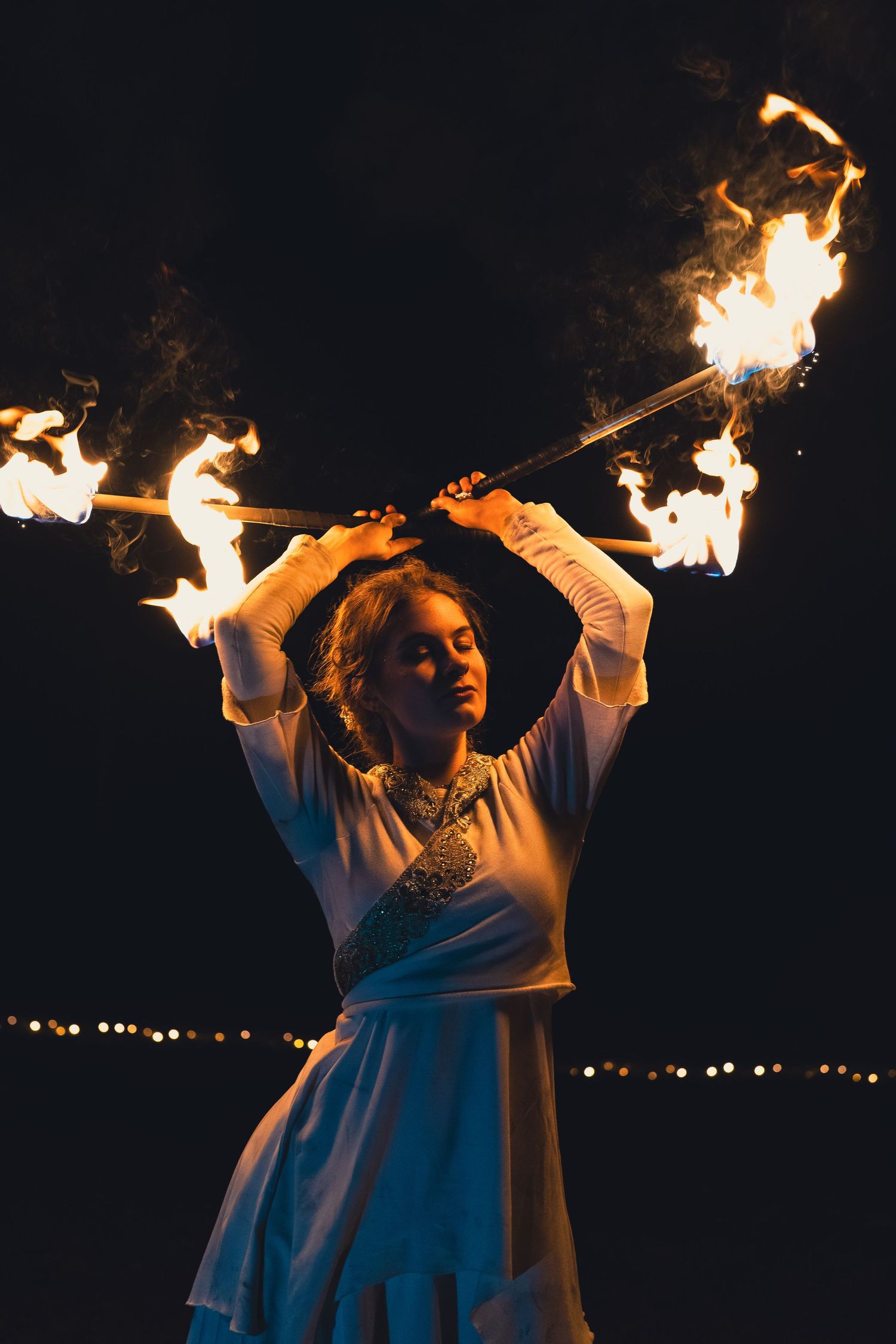 Artistic portrait of a fire dancer with vibrant flames, perfect for cultural event advertising and performance photography.