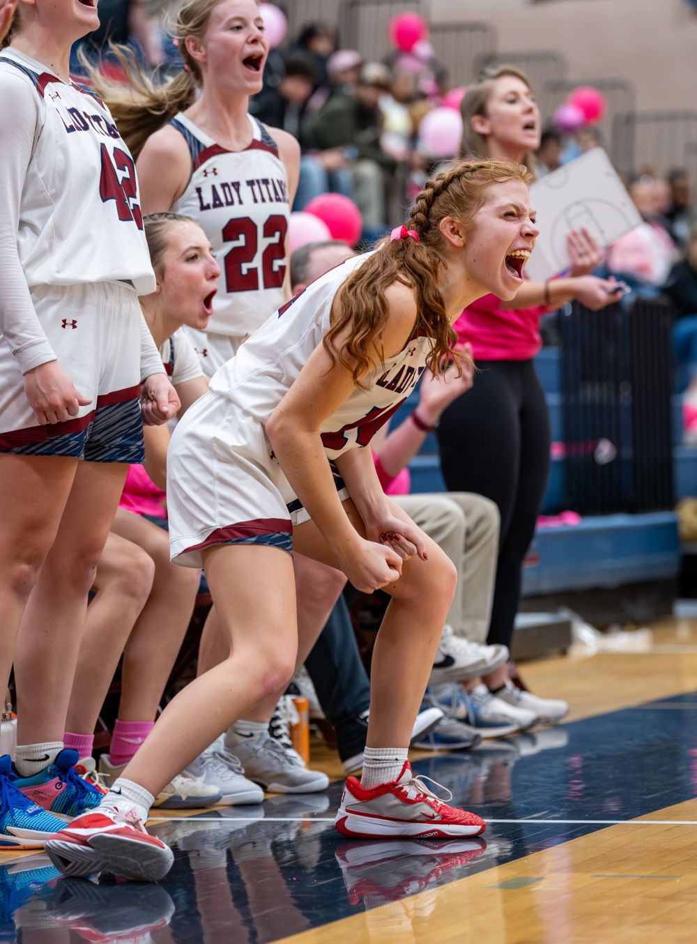 Basketball players on the sideline celebrate enthusiastically during an intense game moment.