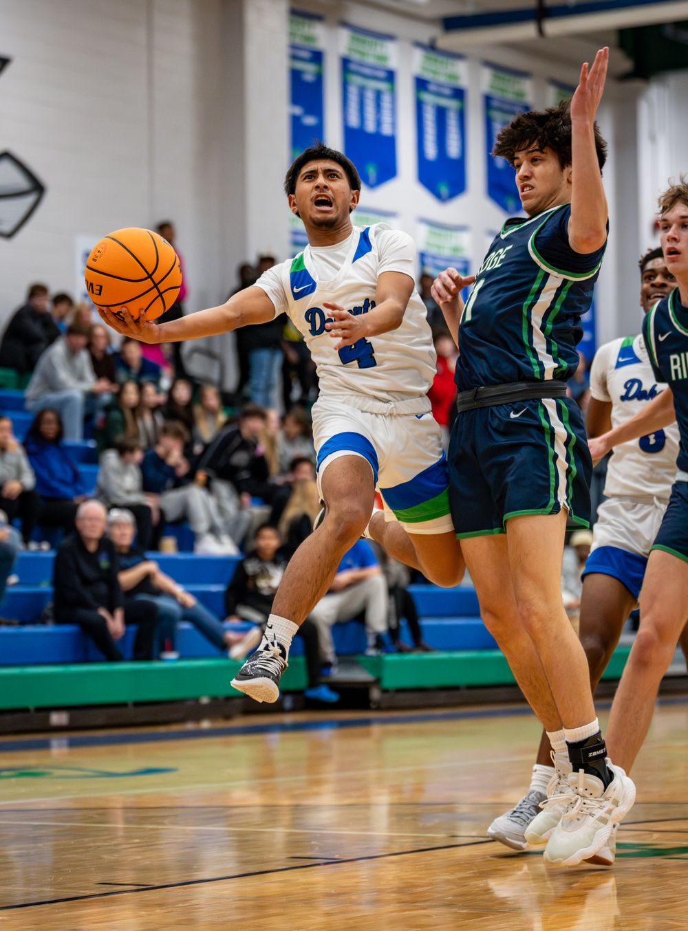 Basketball players from opposing teams compete for ball during intense game action.