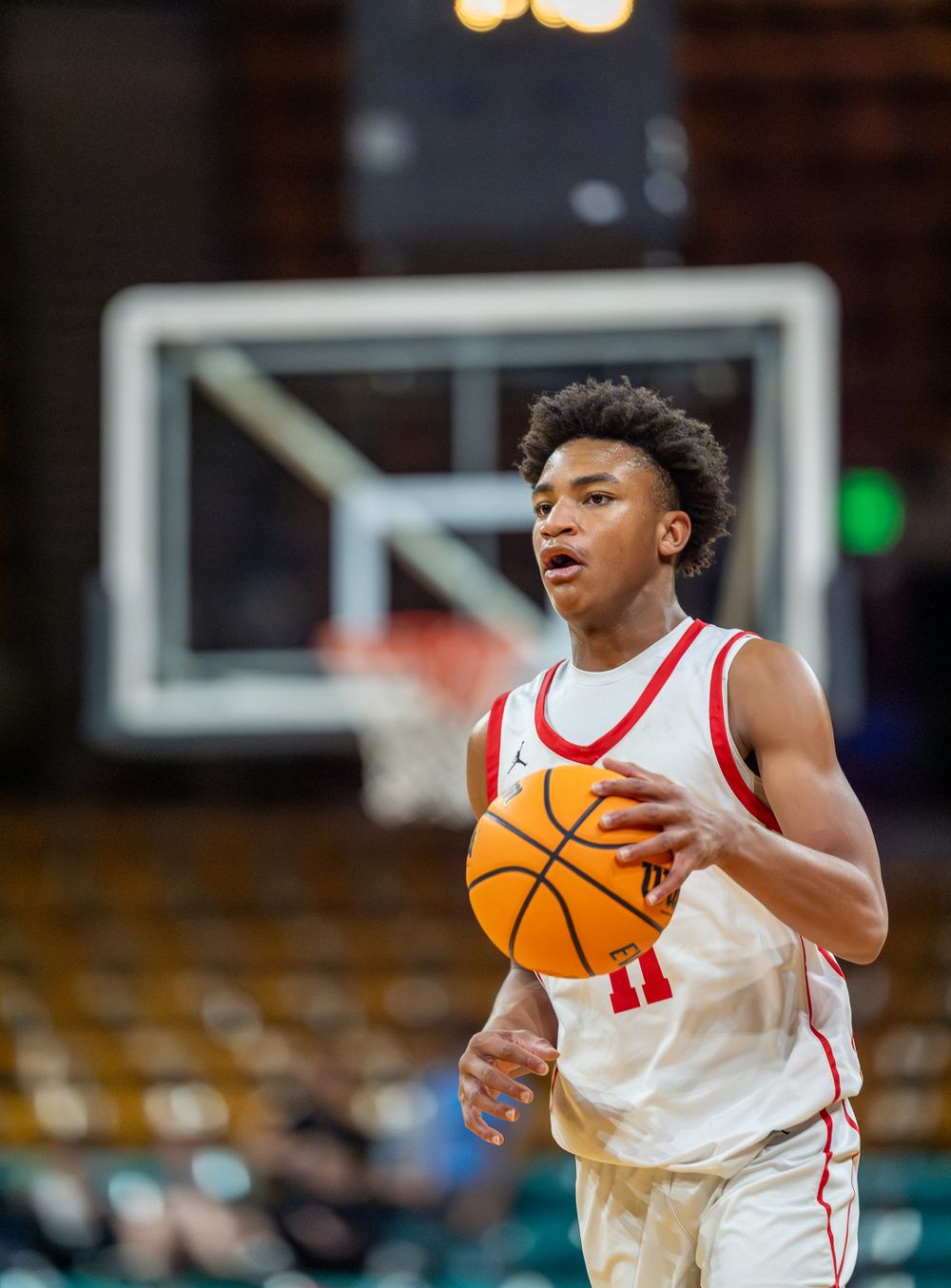 Basketball player in white and red uniform holds ball during game.