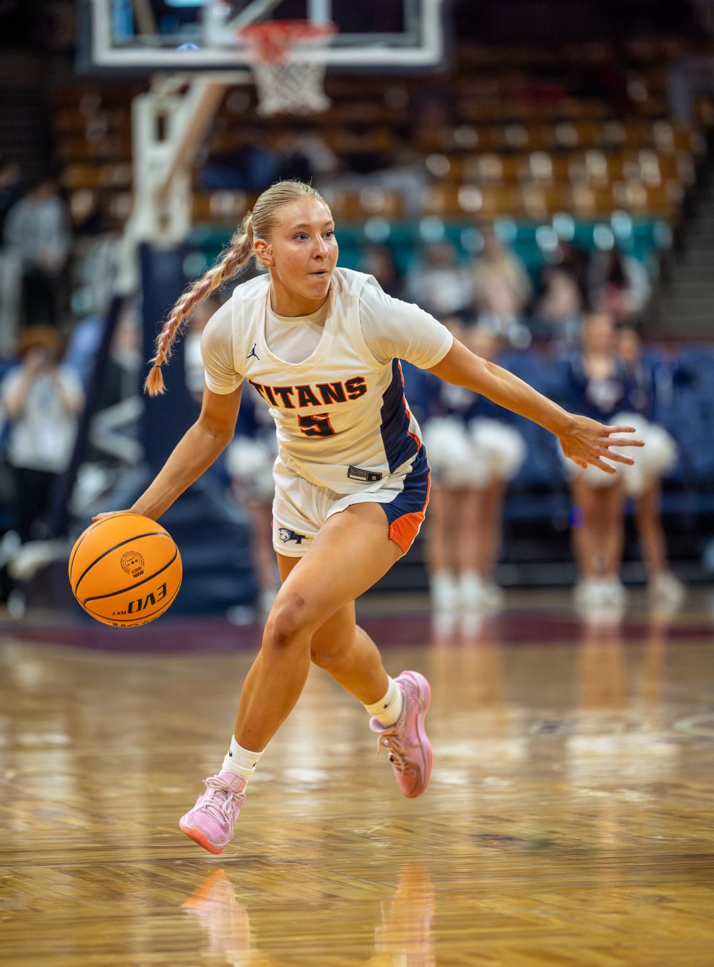 Basketball player dribbles low while driving during game action.