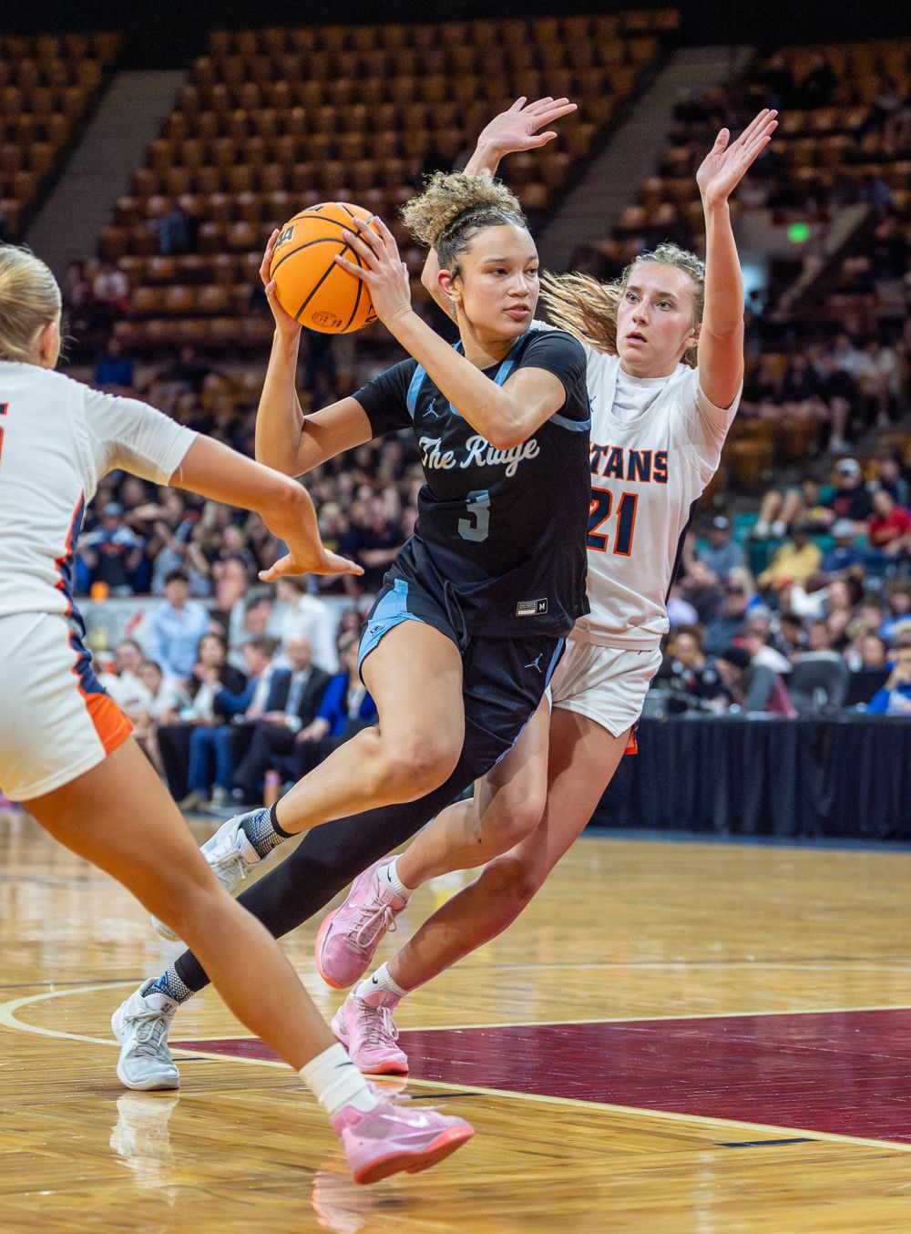 Basketball player drives to the basket while being defended during an intense game.