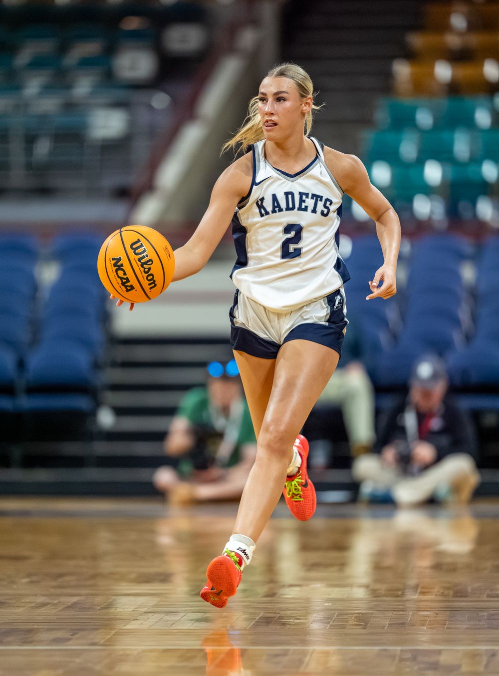 Basketball player dribbles down court during competitive game.