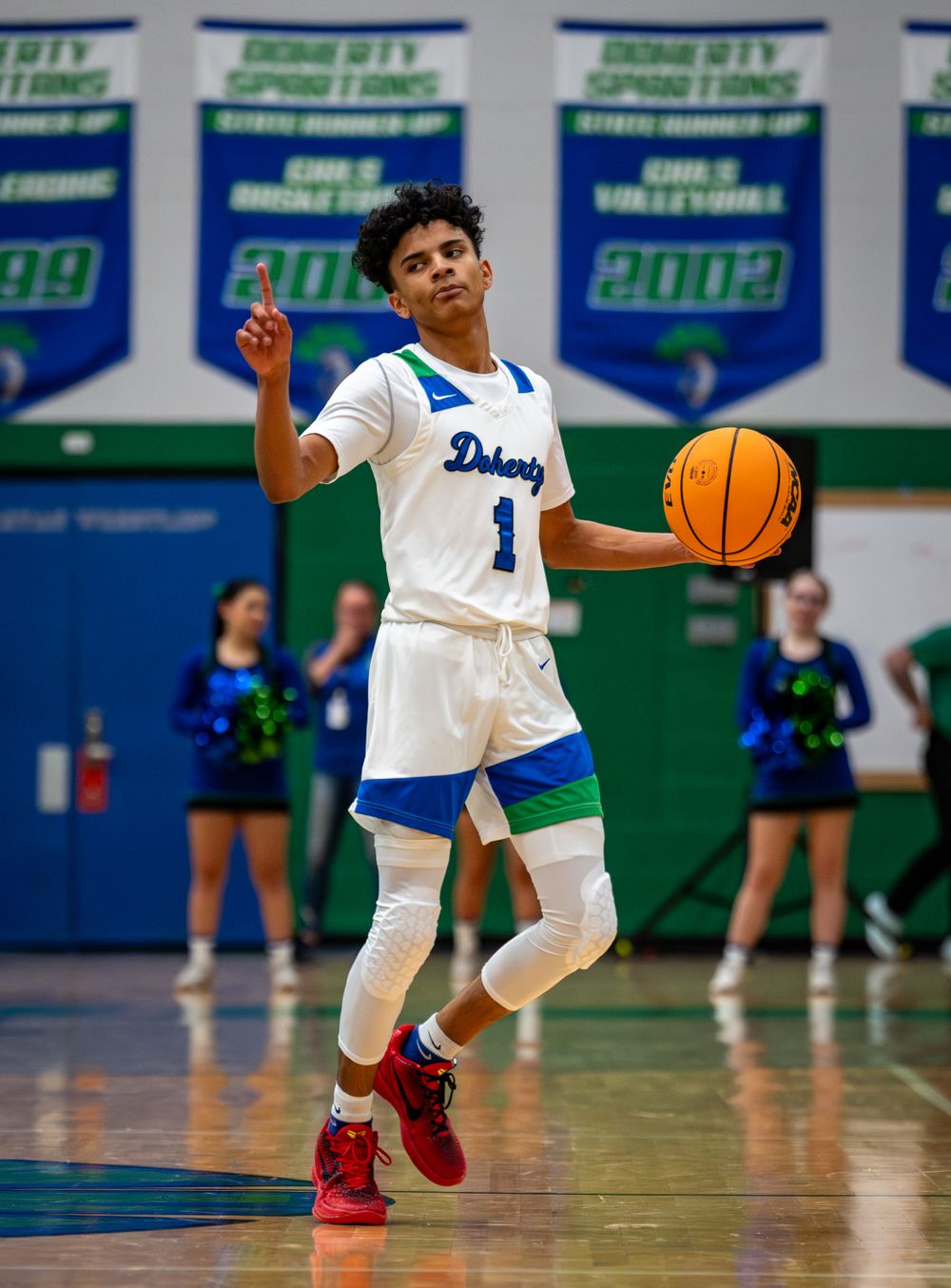 Basketball player in blue and white uniform dribbles on court during game.