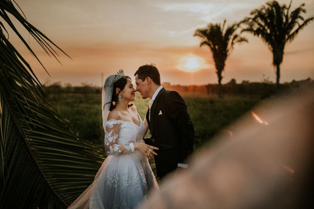 A couple shares an intimate moment at sunset with palm trees silhouetted in the background.