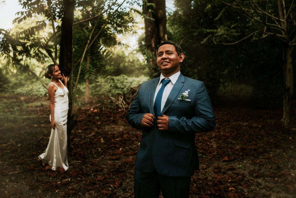 A couple in wedding attire stands separately in a misty forest setting during their wedding photoshoot.