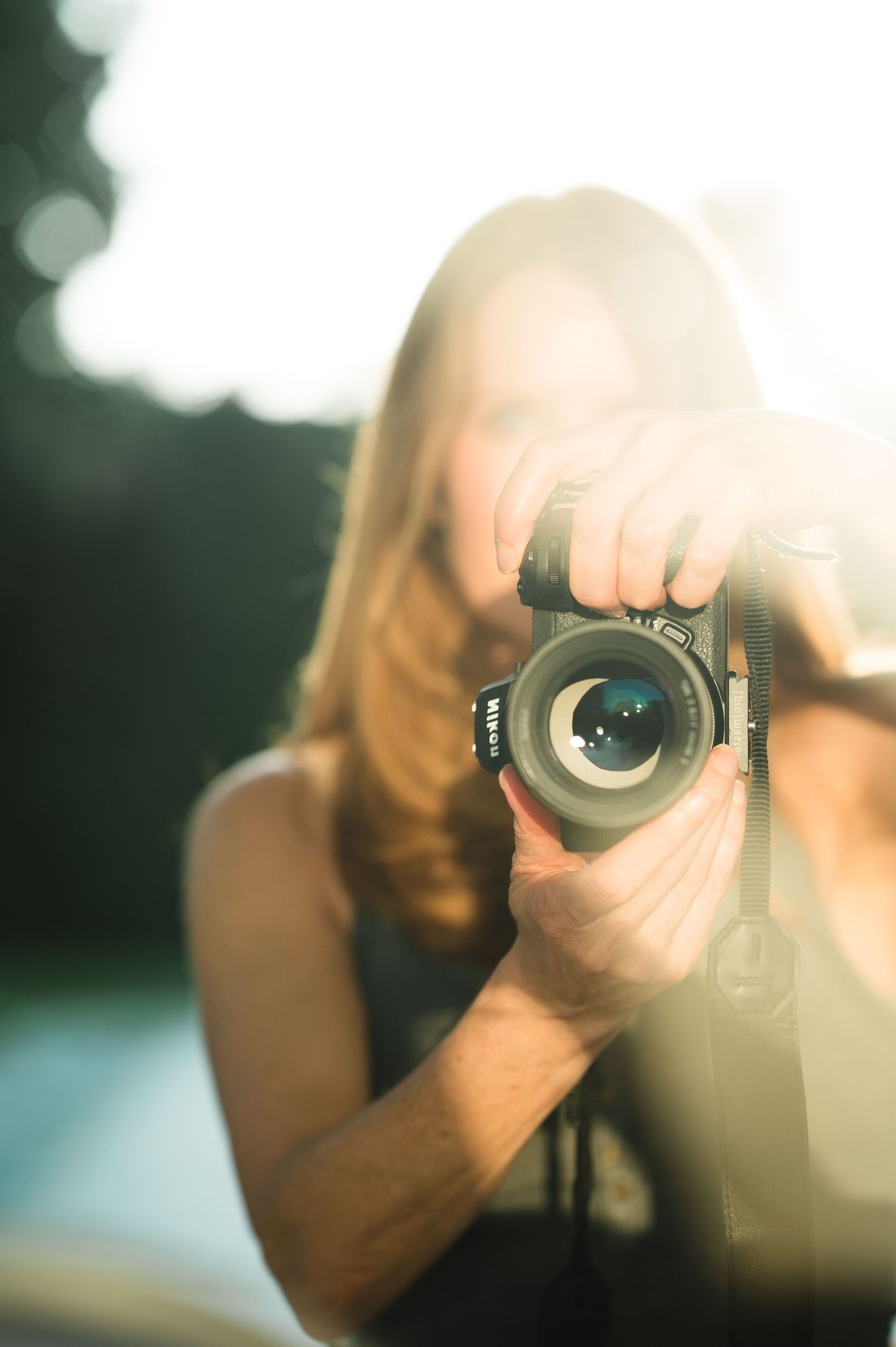 A photographer takes a photo with a DSLR camera creating a creative circular lens reflection effect.