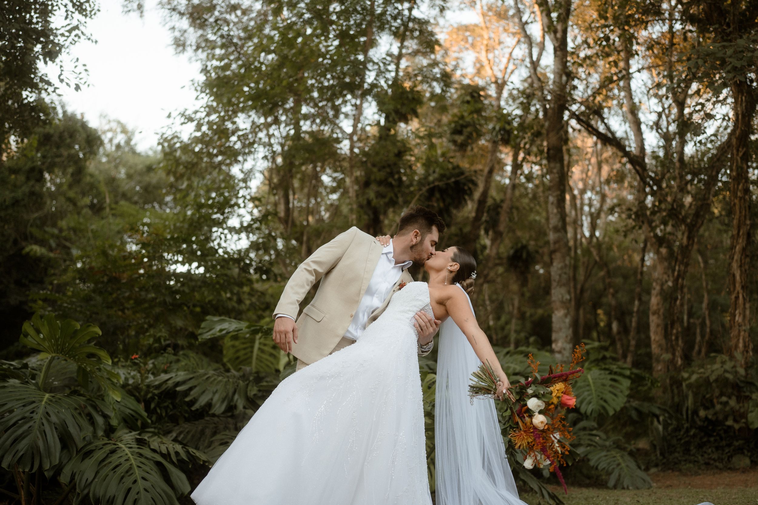 A romantic wedding couple embraces in a lush garden setting.