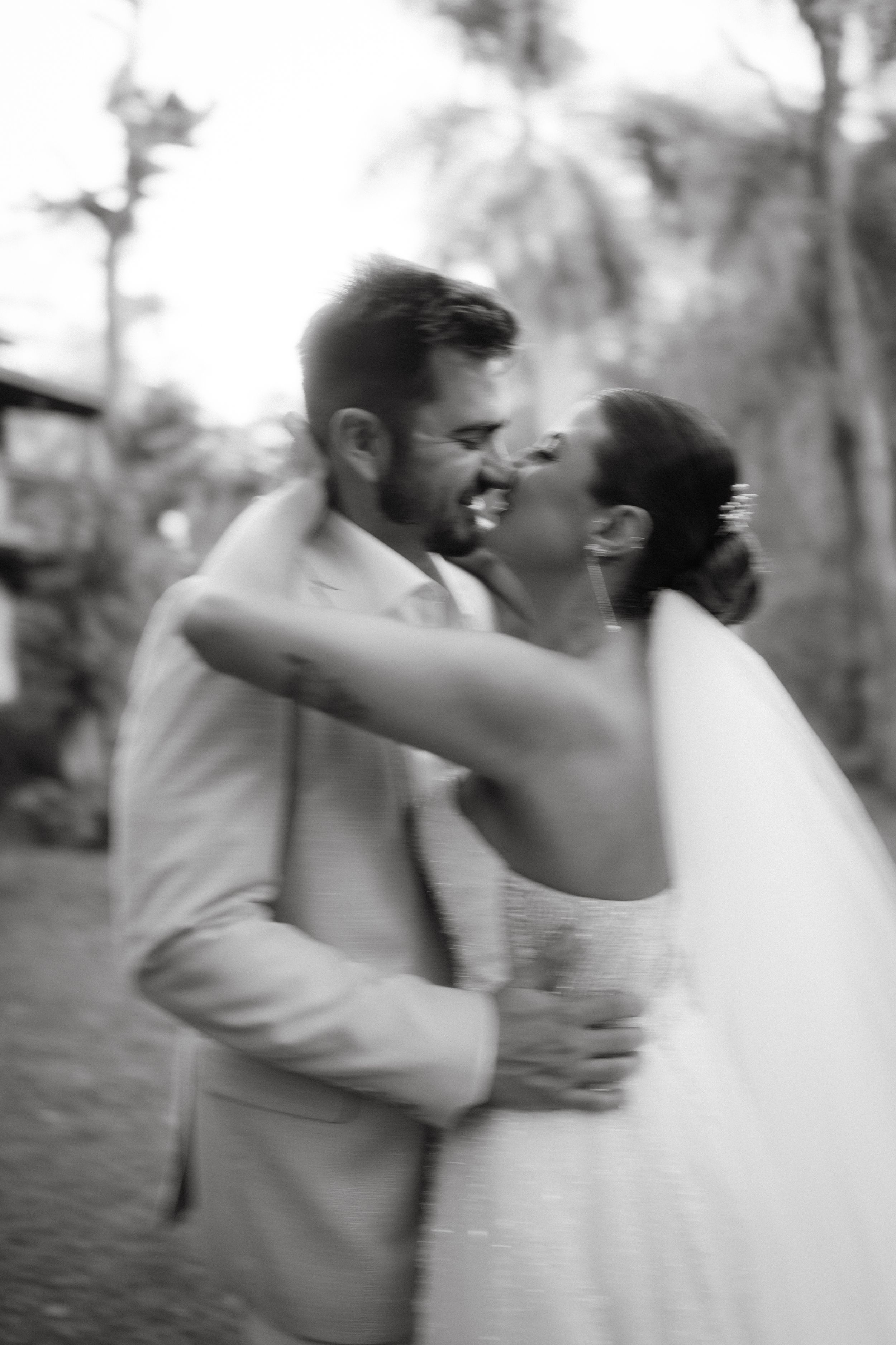 A black and white candid moment of newlyweds dancing outdoors.