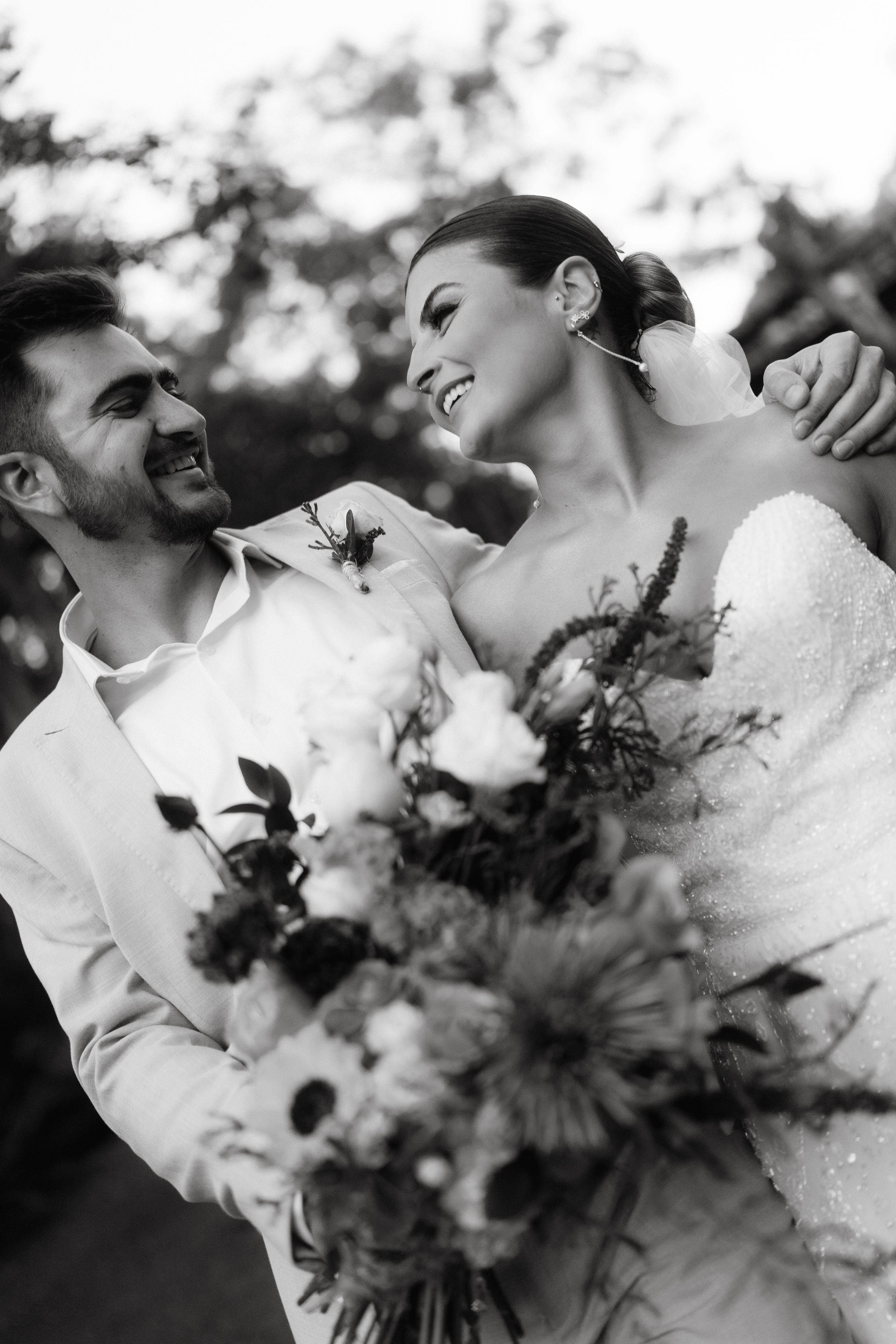 A romantic black and white wedding portrait featuring a beautiful floral bouquet.