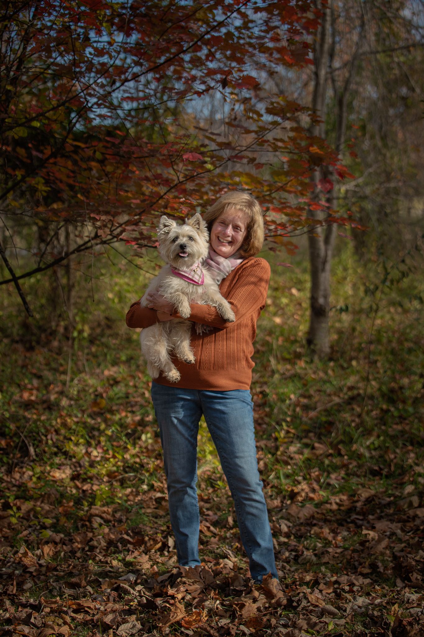 Dog mom holds her terrier in the woods in fall