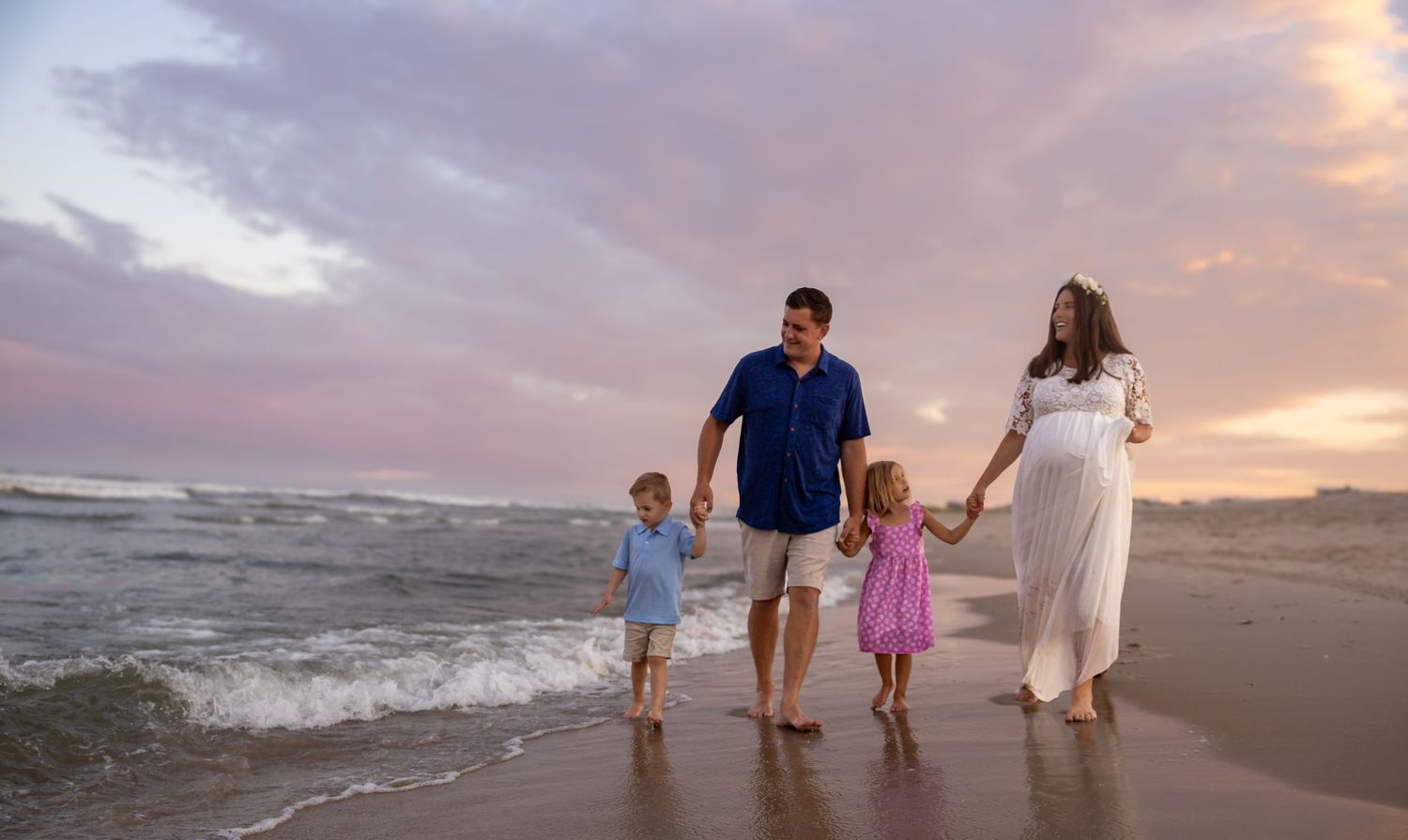 Family walking together along the beach at sunset with waves crashing in the background.