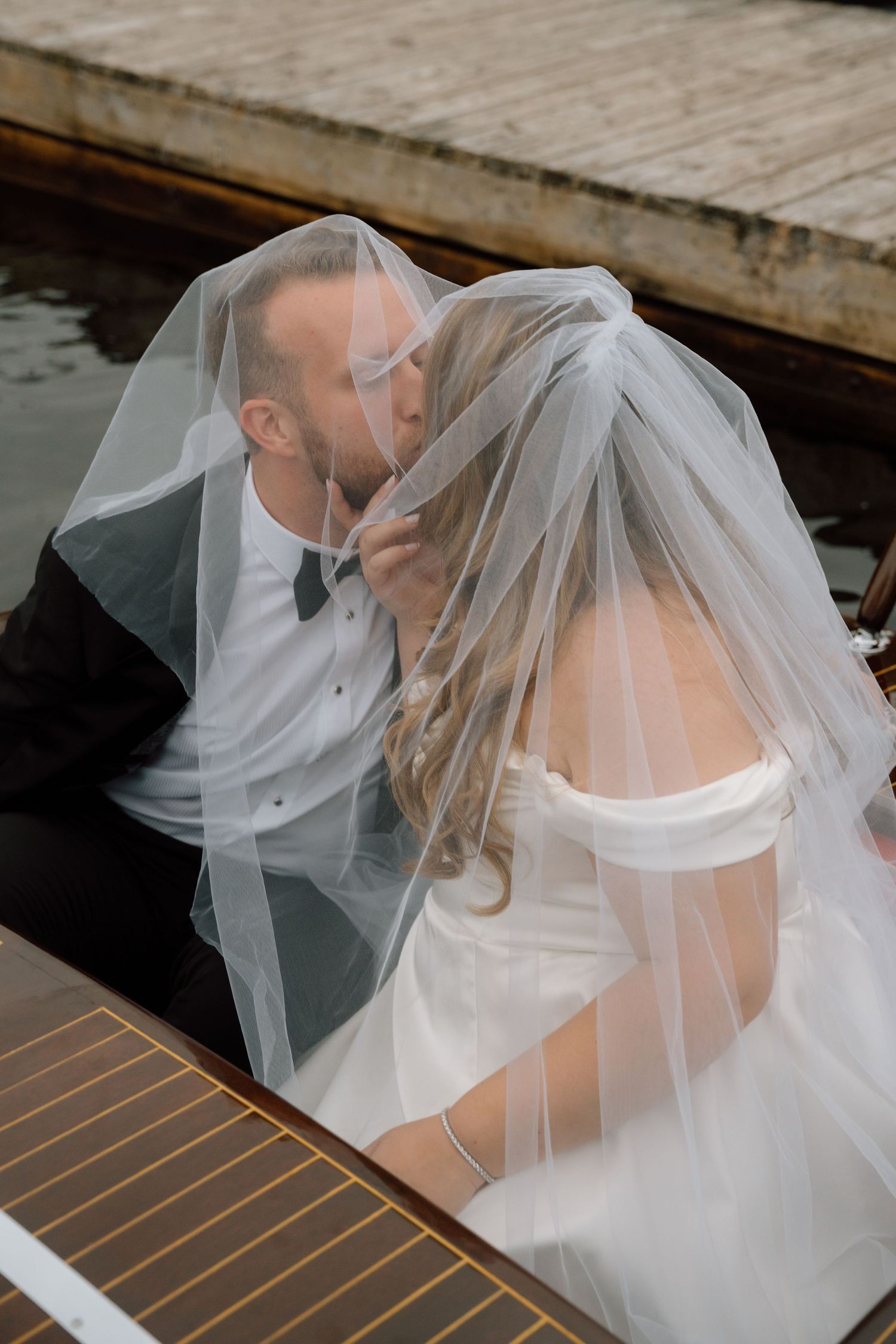 A flowing white veil catches the breeze on a wooden boat deck.
