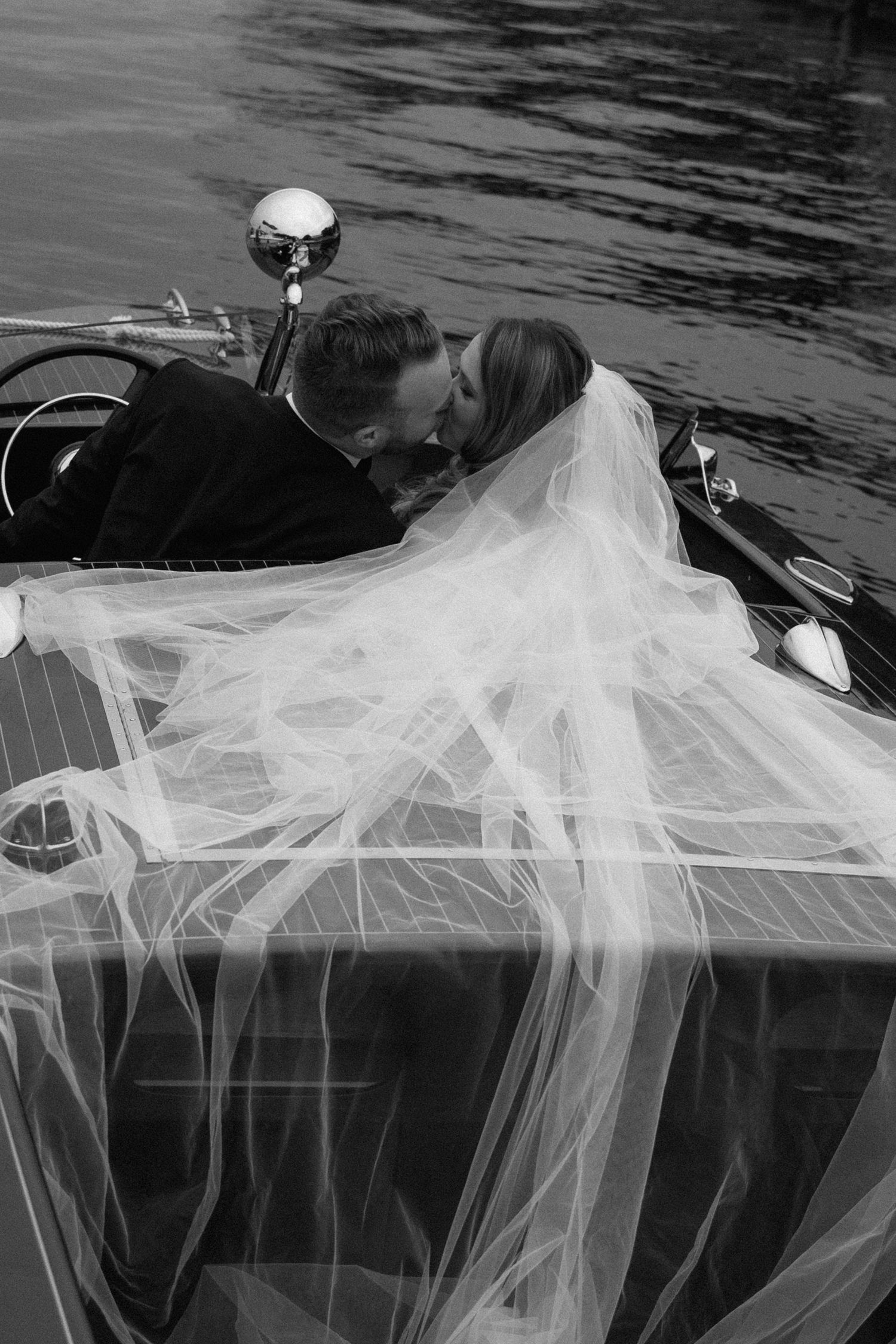 A dramatic black and white shot of a flowing wedding veil draped over a boat's edge.