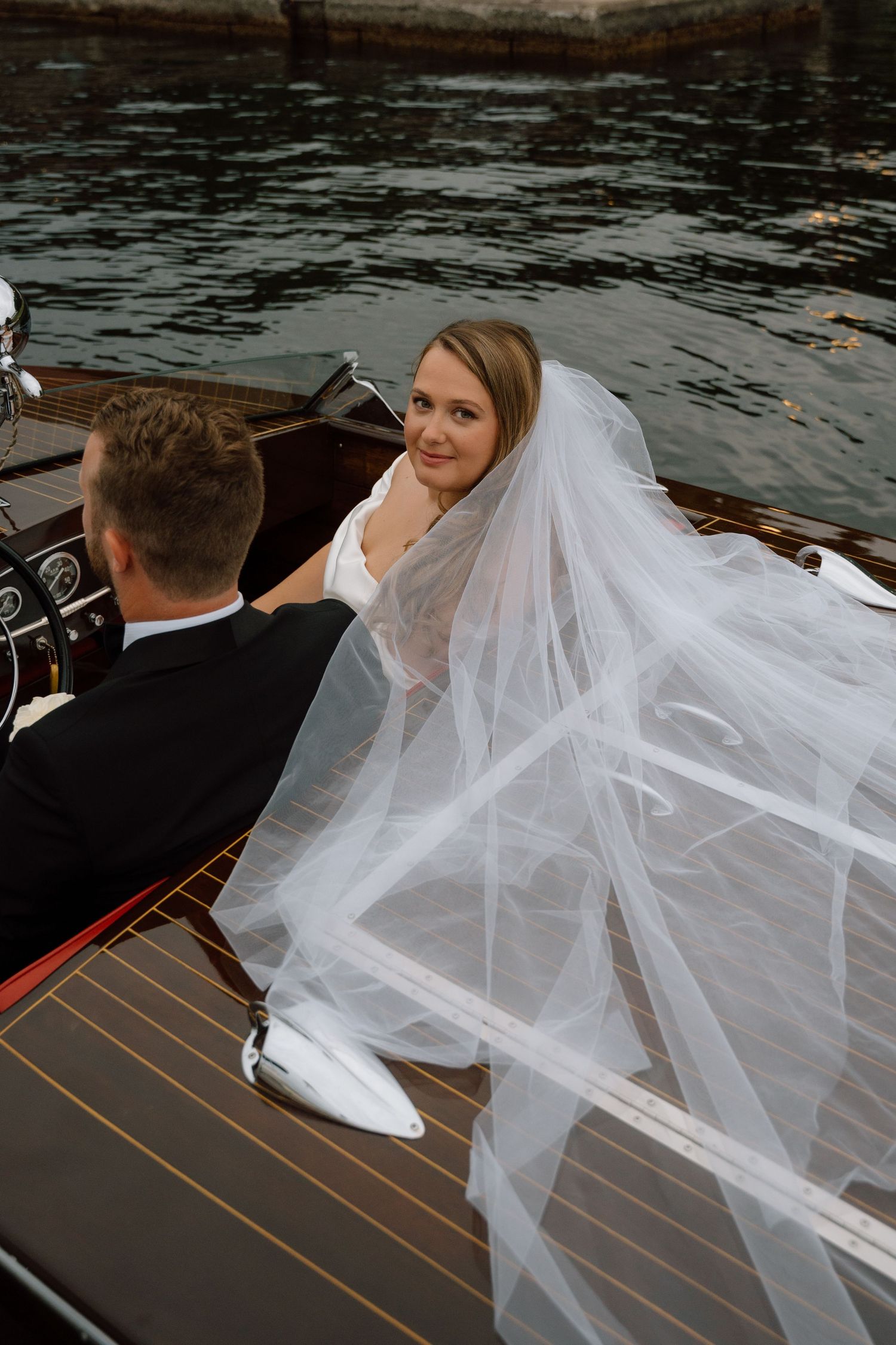 A romantic moment captured on a vintage wooden boat with a flowing veil.