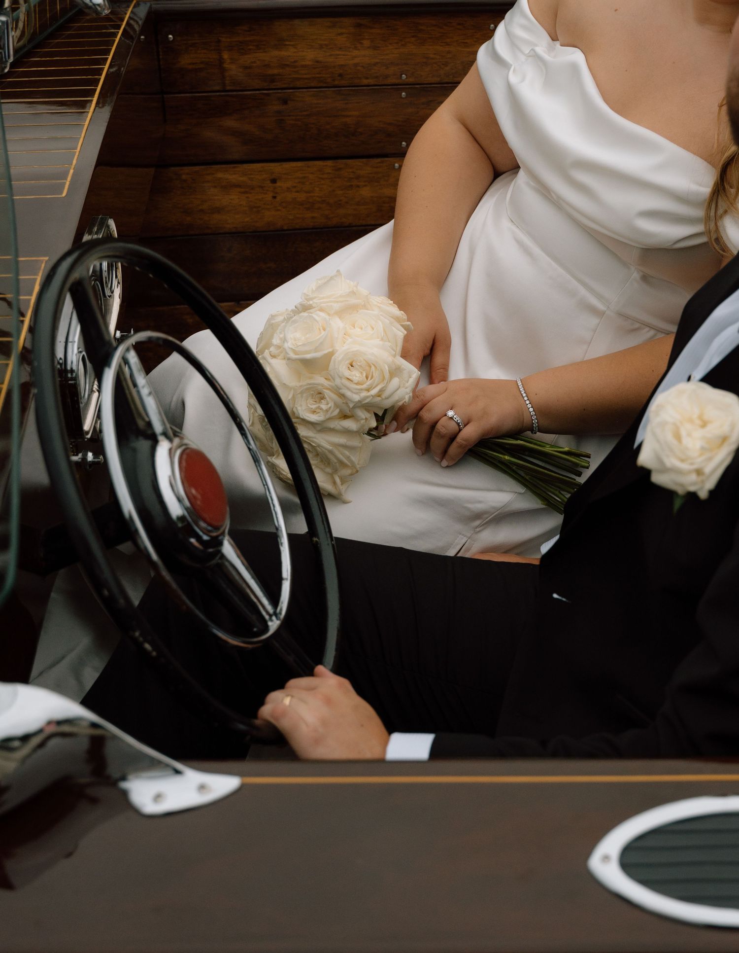 Close-up of a wooden boat's steering wheel and dashboard with elegant wedding details.